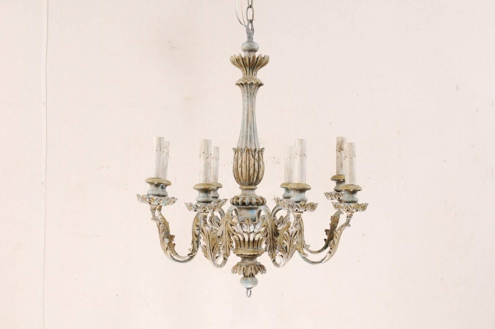 A French eight-light painted wooden chandelier from the mid-20th century. This French chandelier has carved central column with wrapped leaf carvings and fluting details, bottom ring finial, and lovely scrolled metal arms that are decorated with