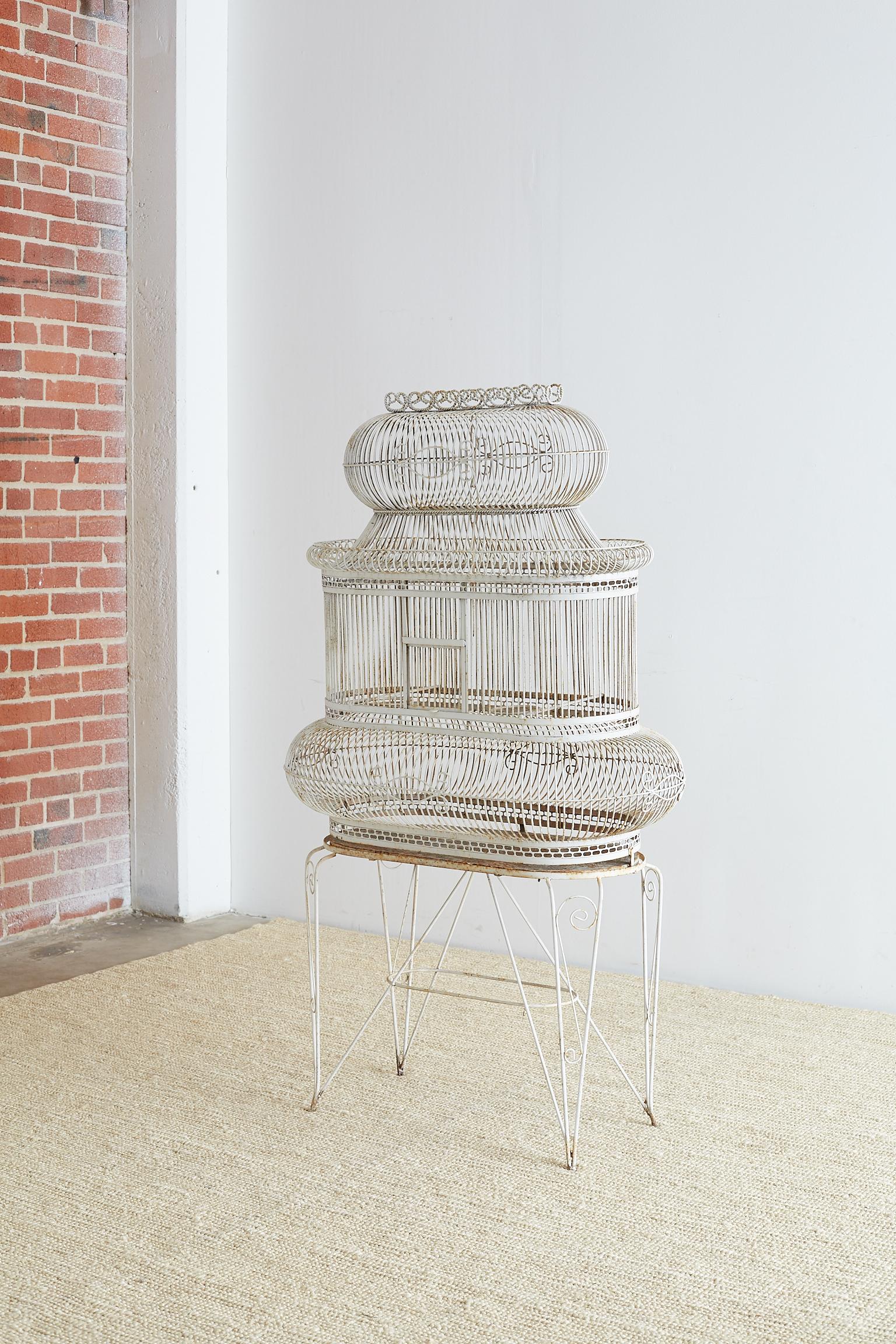 Fabulous French balloon birdcage on stand. Handmade from wrought iron and finished in a distressed white paint with a patinated metal patina. Beautifully shaped with balloon style oval forms and scroll motifs. Supported by an oval Stand with