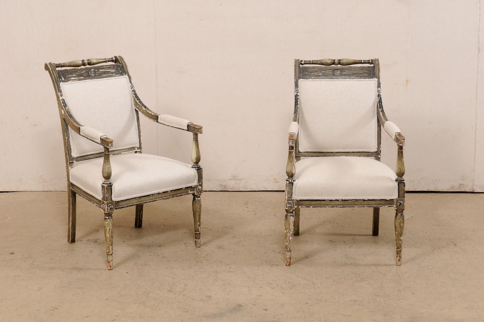 A French pair of Empire style armchairs, with their original painted finish, from the 19th century. These antique fauteuils from France each feature beautifully arched backs, rectangular in shape with upholstered back-centers framed within wood
