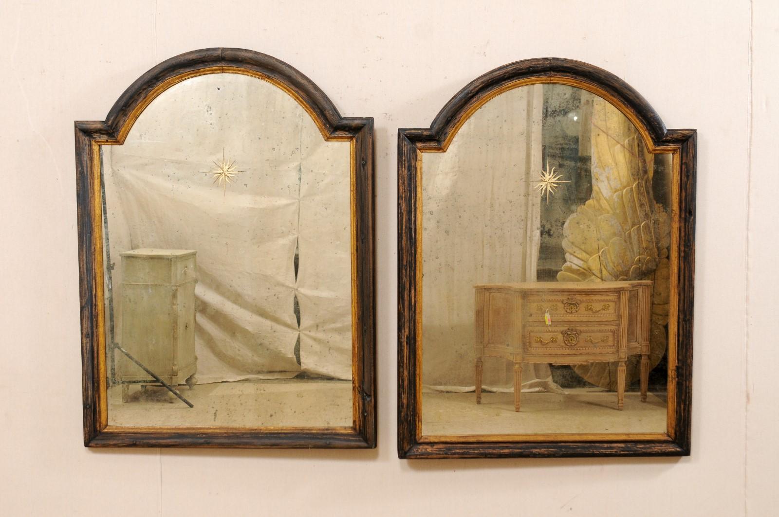 A French pair of 19th century mirrors with sunburst églomisé center. This antique pair of mold-trimmed wooden mirror surrounds from France each feature a convexly arched top, with straight lines making up the sides and bottom. The center glass is