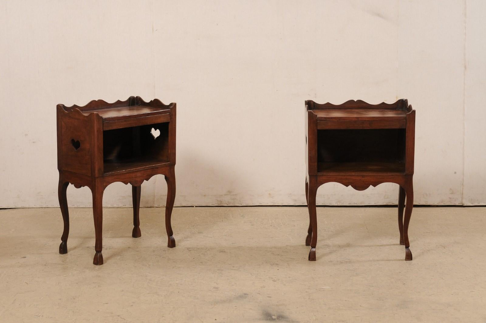 A French pair of carved-wood side tables with open shelf from the turn of the 19th and 20th century. These antique fruitwood tables from France each feature a top with beautifully scalloped raised lip at each side and back, atop a case that houses