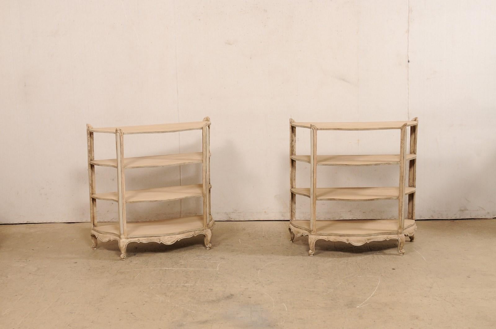 A French pair of painted bow-front wood display shelves from the mid 20th century. These vintage open display shelving units from France, each standing just shy of 3 feet in height, are fashioned with four levels of open shelving supported within