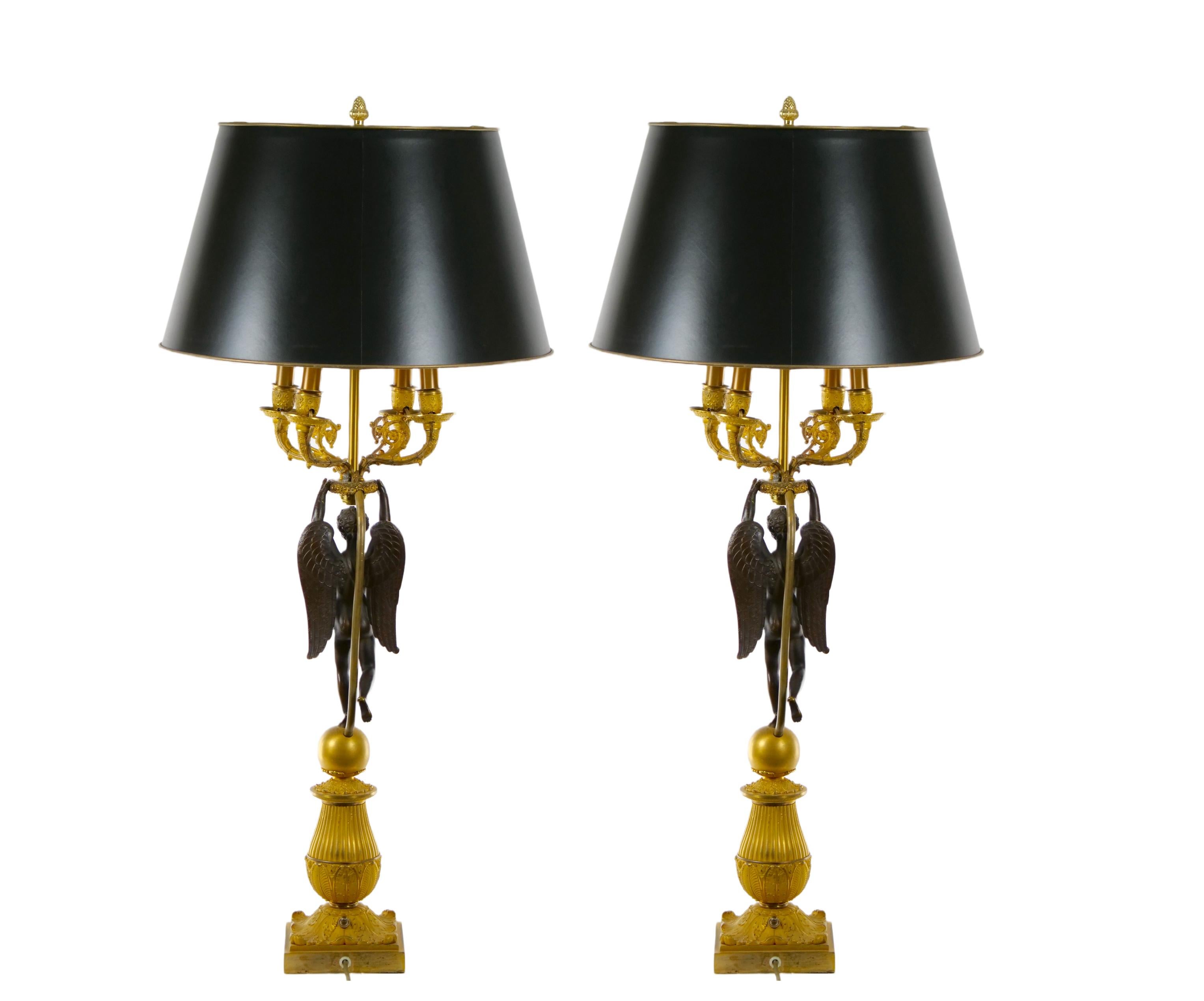 Wonderful pair of French Napoleon III Empire style gilt doré and patinated bronze neoclassical four-arm candelabra with finely cast decorated detail. Each lamp features a classical winged putti figure positioned on a round ball mounted on a tiered