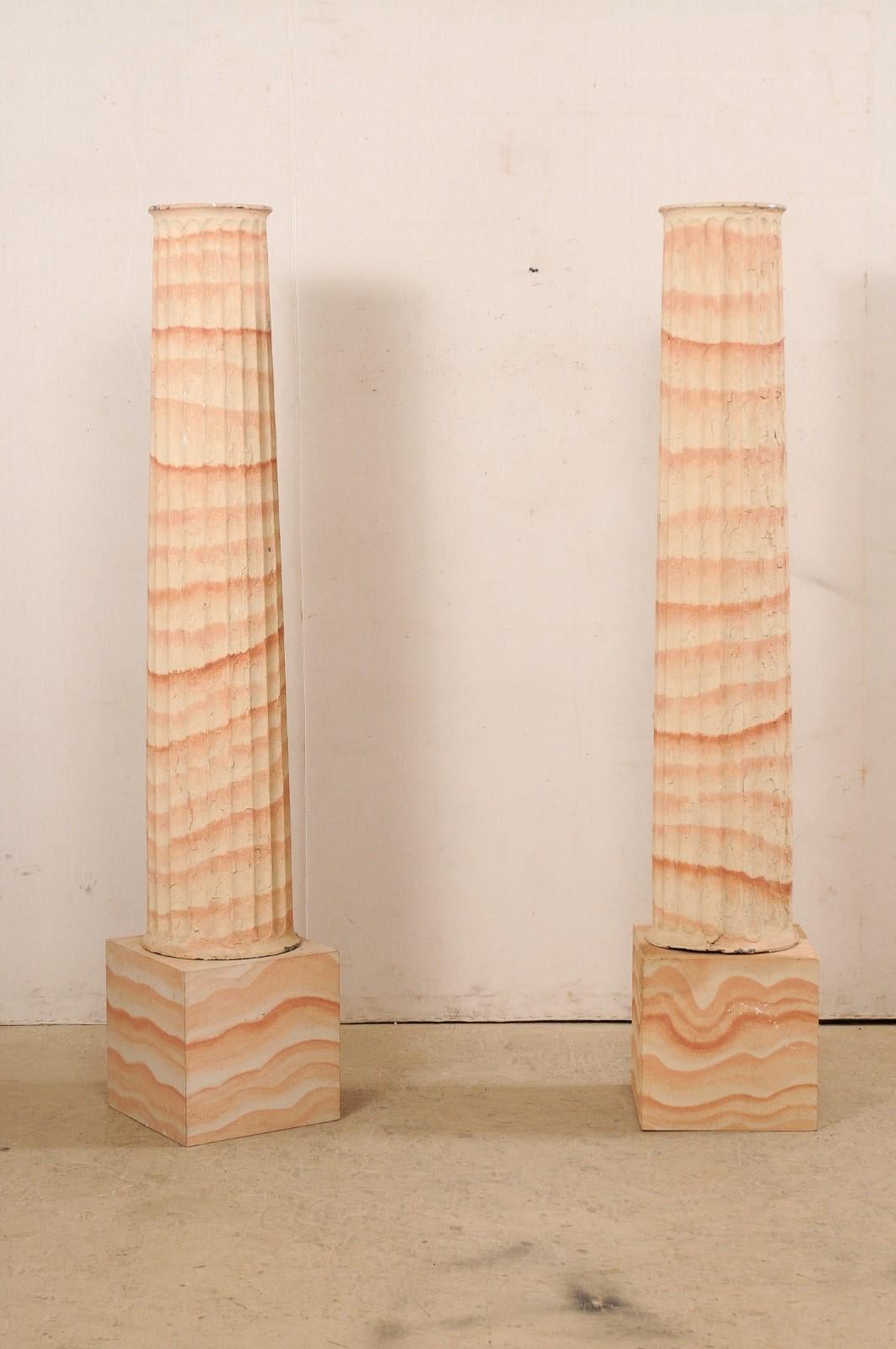 A French pair of iron columns with textured artisan hand-painted finish from the turn of the 19th and 20th century. These antique pillars from France, standing just shy of 6.5 feet in height, have rounded and fluted bodies that are thicker at their