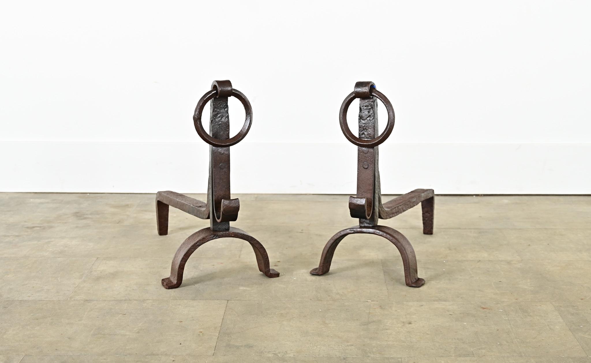 A charming pair of French hand-forged, wrought iron fireplace andirons–or chenets–made in the 18th century. Somewhat Gothic in style, they have a reddish brown patina from oxidation of the iron and centuries of exposure to high heat. The hefty