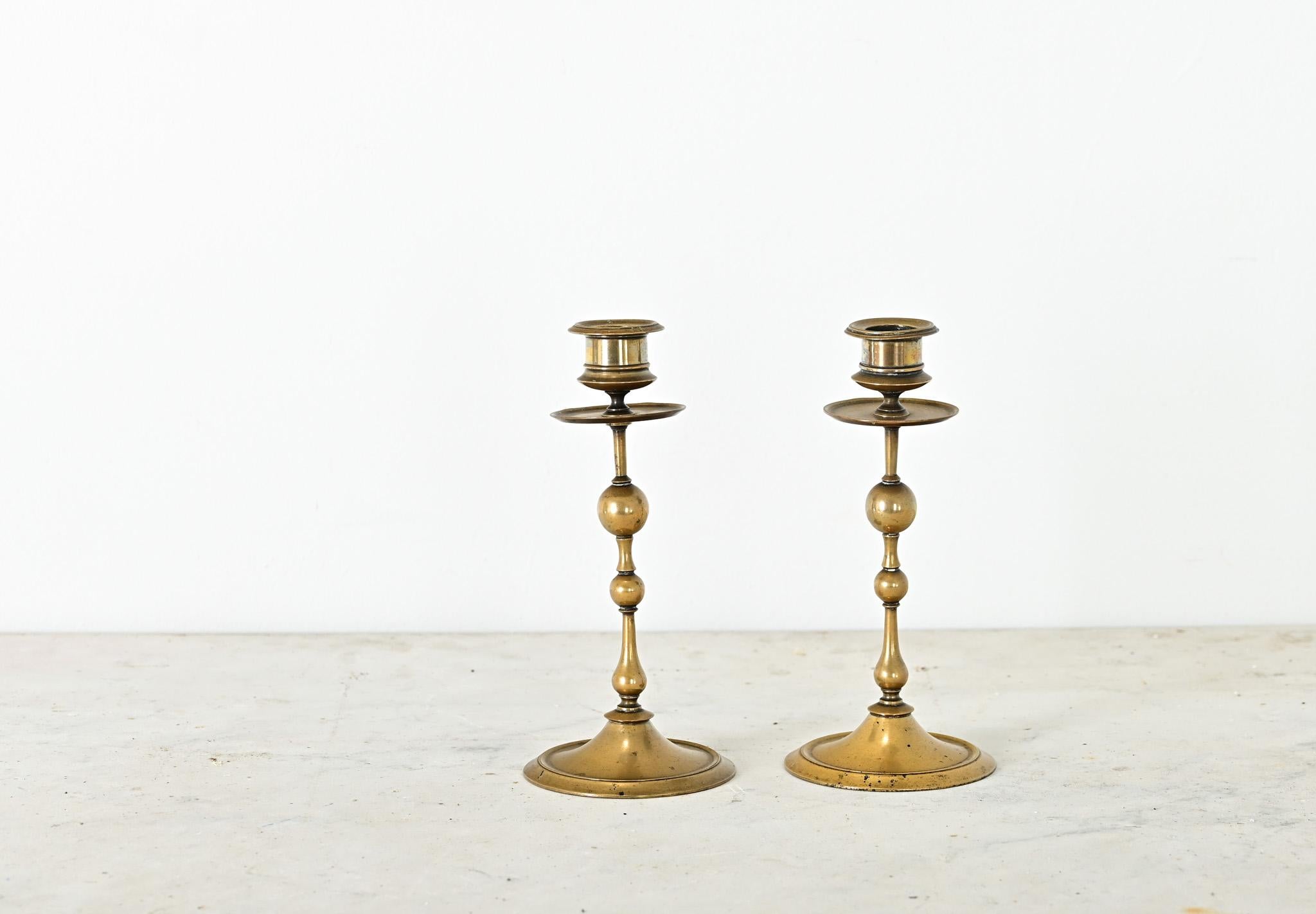 Un par de candelabros franceses de latón macizo de la década de 1800, inspirados probablemente en las formas juguetonas de los ejemplos noruegos y suecos de la ola creativa del Biedermeier. Sus formas atenuadas se caracterizan por la alternancia de