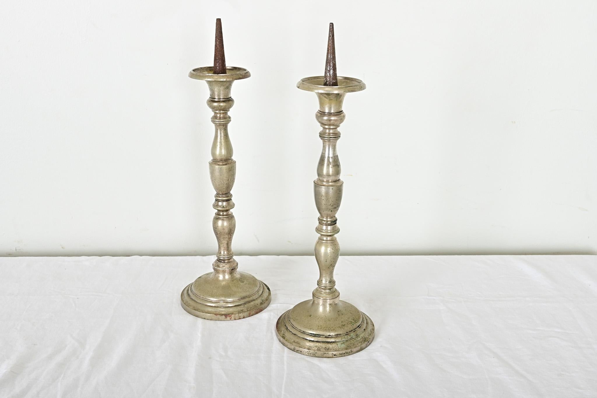 Con il classico profilo Luigi XVI, questi sostanziosi candelieri in peltro provenienti dalla Francia del XIX secolo faranno bella mostra di sé su qualsiasi caminetto o tavolo. Le forme a balaustro presentano una patina morbida, con una finitura