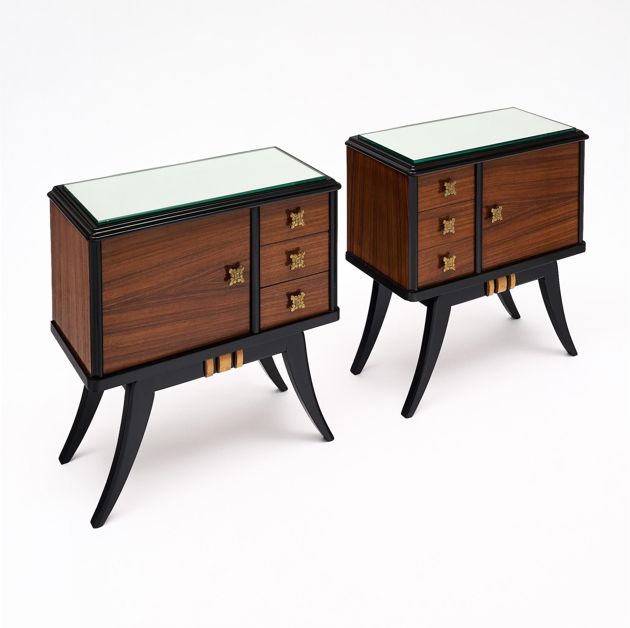 Pair of French side tables from the Art deco period. Rosewood and ebonized wood are combined to form these delicate and elegant side tables, enhanced with gilt brass elements in the Art Deco style. We love the flaring legs and the mirrored tops.
