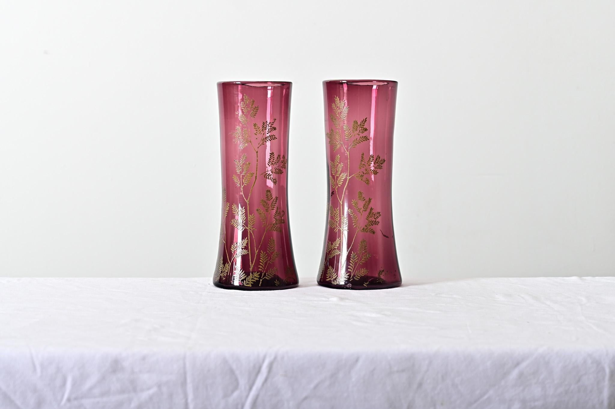 Fantastic pair of handmade, Art Nouveau amethyst glass vases from France, circa 1900 if not earlier. The cylindrical glass forms are a deep amethyst-cranberry tone with delicate illustrations in painted gold of branches, such as those from a willow