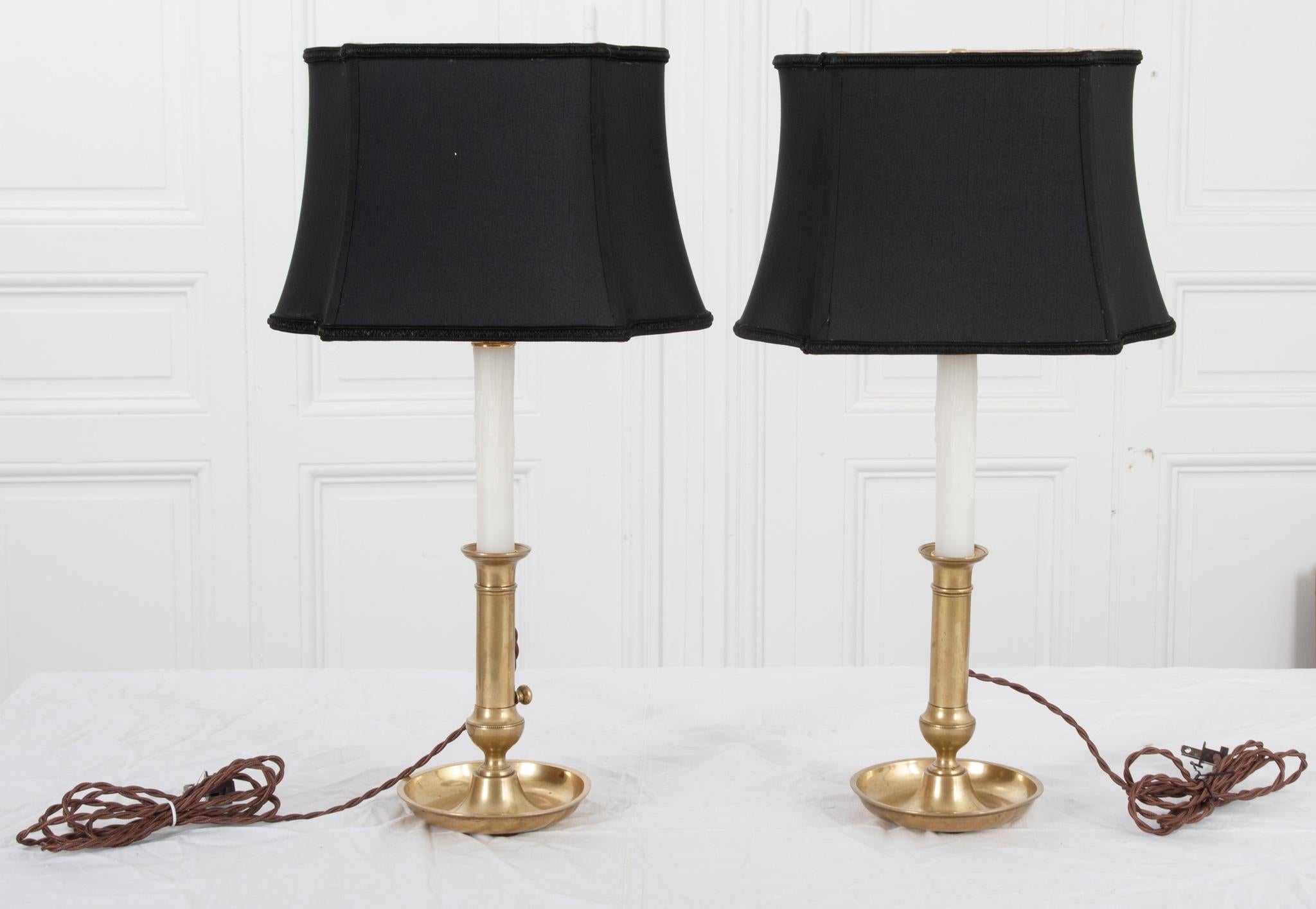 This is a charming pair of lamps with bases made from brass candlestick holders. Fixed with new, shaped fabric shades with cording. Wired for the US using UL listed parts. The sleek braided cording has been threaded into the lamp through an opening