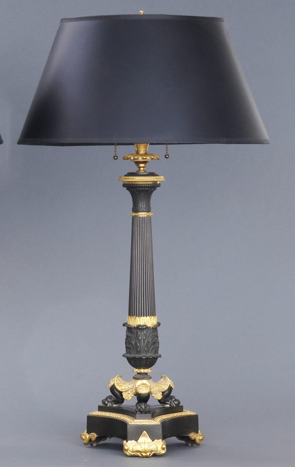 Pair of exceptional French Charles X period bronze and ormolu candlestick lamps with a tapering reeded and acanthus cast column on a tripod base with claw feet, stepped base on ormolu fleur-de-lis feet.