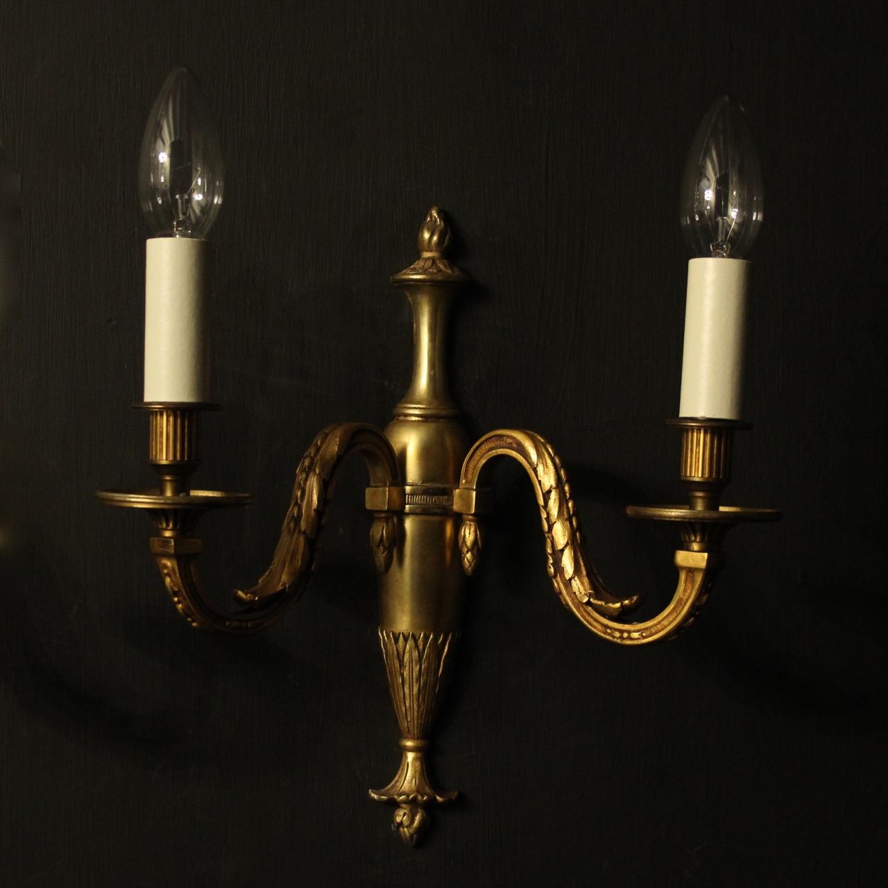 A French pair of gilded bronze twin branch antique wall lights, the leaf clad square gauge scrolling arms with circular bobeche drip pans and reeded candle sconces, issuing from a bulbous tapering leaf back plate, nice color and scale. Fully rewired
