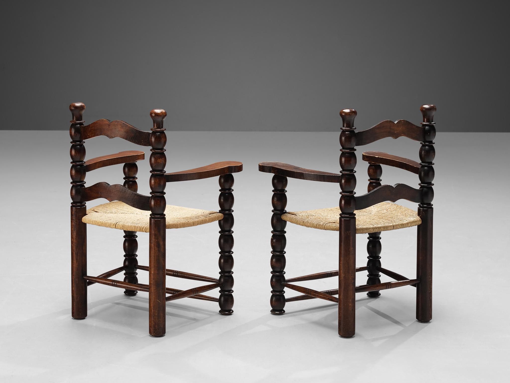 Pair of armchairs, stained wood, rush, France, 1940s.

Decorative pair of French armchairs. The stained wooden frame has multiple carved details that add up to a complex whole. Carved lines and circular ends, straight and round parts come together