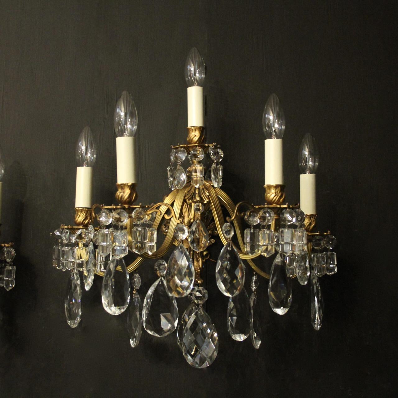 A French pair of gilded bronze and crystal five arm double tiered antique wall lights, the reeded scrolling arms with leaf bobeche drip pans and bulbous leaf candle sconces, issuing from a foliated cartouche backplate and decorated overall with