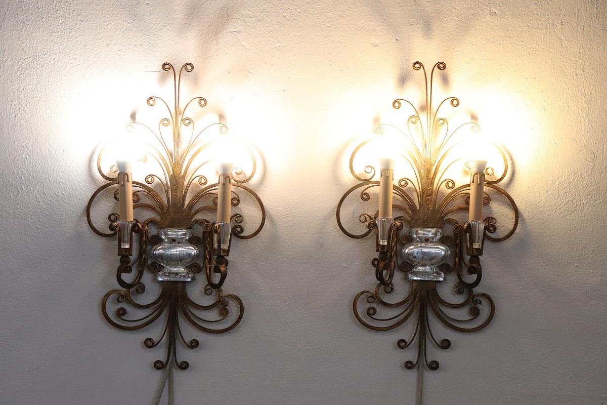 Rare pair of sconces by Maison Baguès, France circa 1950s. Made of gilded iron with delightful crystal details. The design is unique, featuring curls and swirls that give a special decorative effect. The gold color gives a distinctive touch of