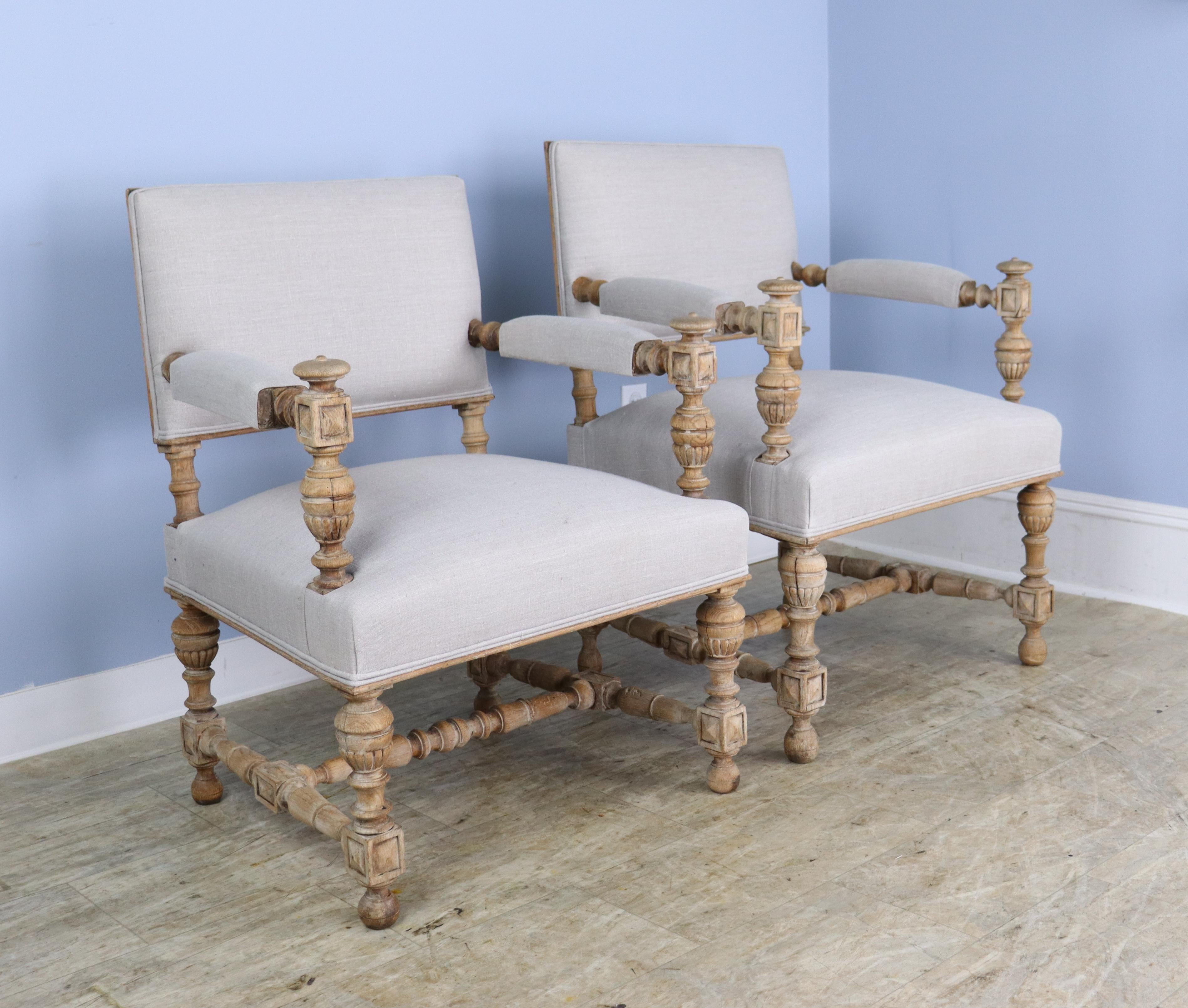 A gorgeous pair of his and hers French oak armchairs, bleached and newly upholstered in cream linen for a clean, modern look.  The formality of the intricate turnings and carvings is downplayed by the bleaching and gives the pair a beachy, country