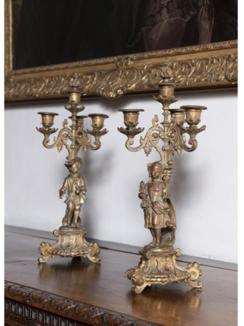 Pair of bronze candelabras with four branches having two different figures standing at the bottom part.
France, circa 1920.