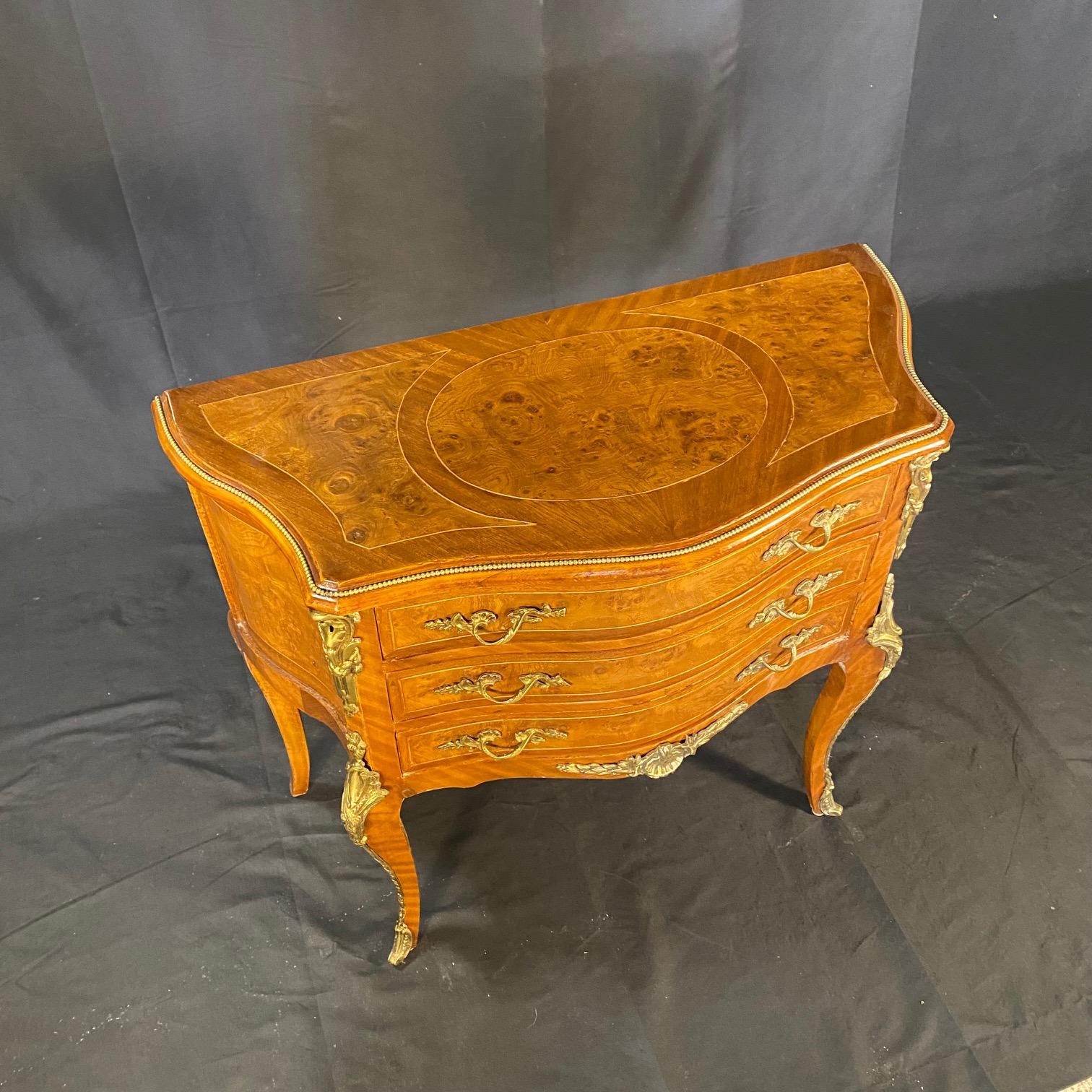 Paire de petites commodes Louis XV, pouvant également servir de tables d'appoint ou de tables de nuit. Chacune comprend trois tiroirs, tous avec incrustation de noyer ronce et de belles poignées, ainsi que des accents de bronze doré sur le tablier