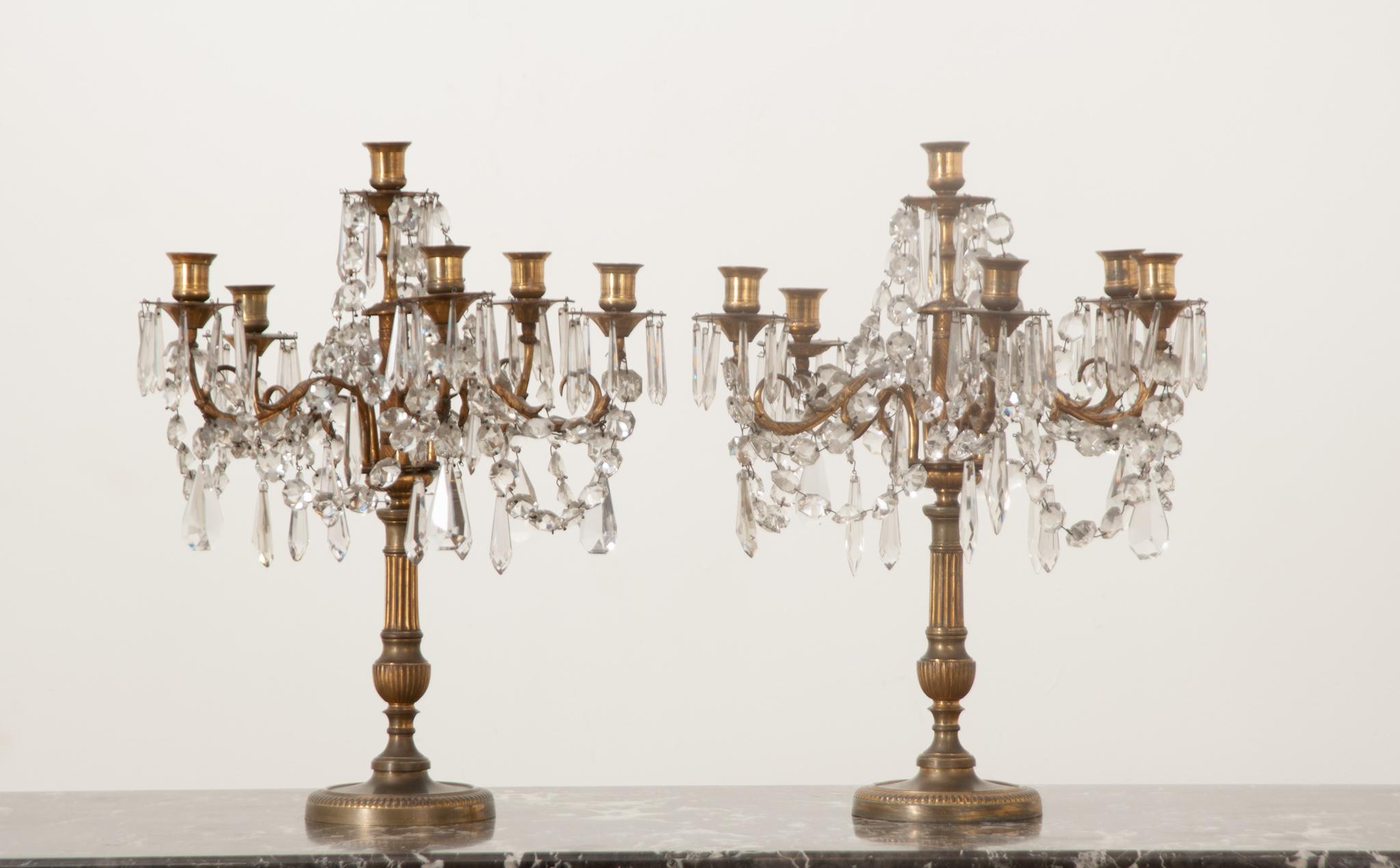 This dazzling pair of French girandoles or table chandeliers are in wonderful antique condition. Each fixture is centered with a gilt bronze Louis XVI style candelabra base with six sweeping arms and candle cups. The arms of the girandoles are