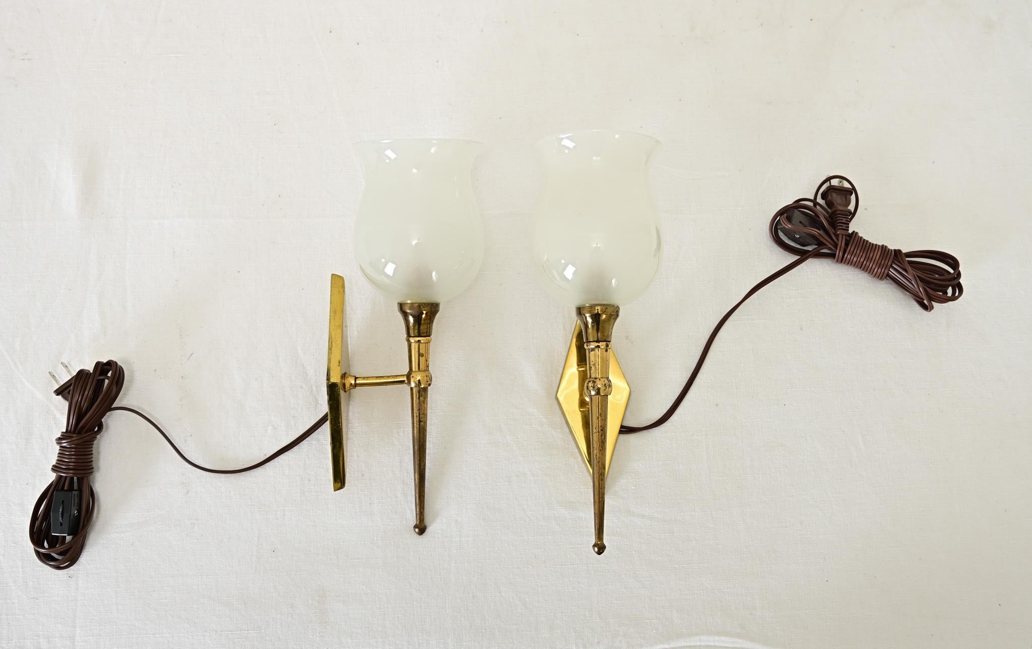 Questa piccola coppia di applique in ottone francese della metà del secolo scorso (alla maniera del designer Jean Perzel) ha un classico profilo a torchiera che illuminerà dolcemente qualsiasi spazio, dalle toilette ai corridoi. Ogni apparecchio si