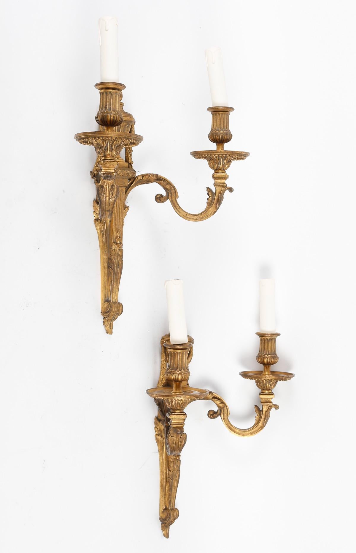 19th Century French Pair of chiseled and gilded bronze wall-lights, the fluted barrel, from which acanthus leaves escape in scrolls forming two arms of light, and crowned with a fire pot, neck-shovels with twisted flutes, heart, hoes with leaves of