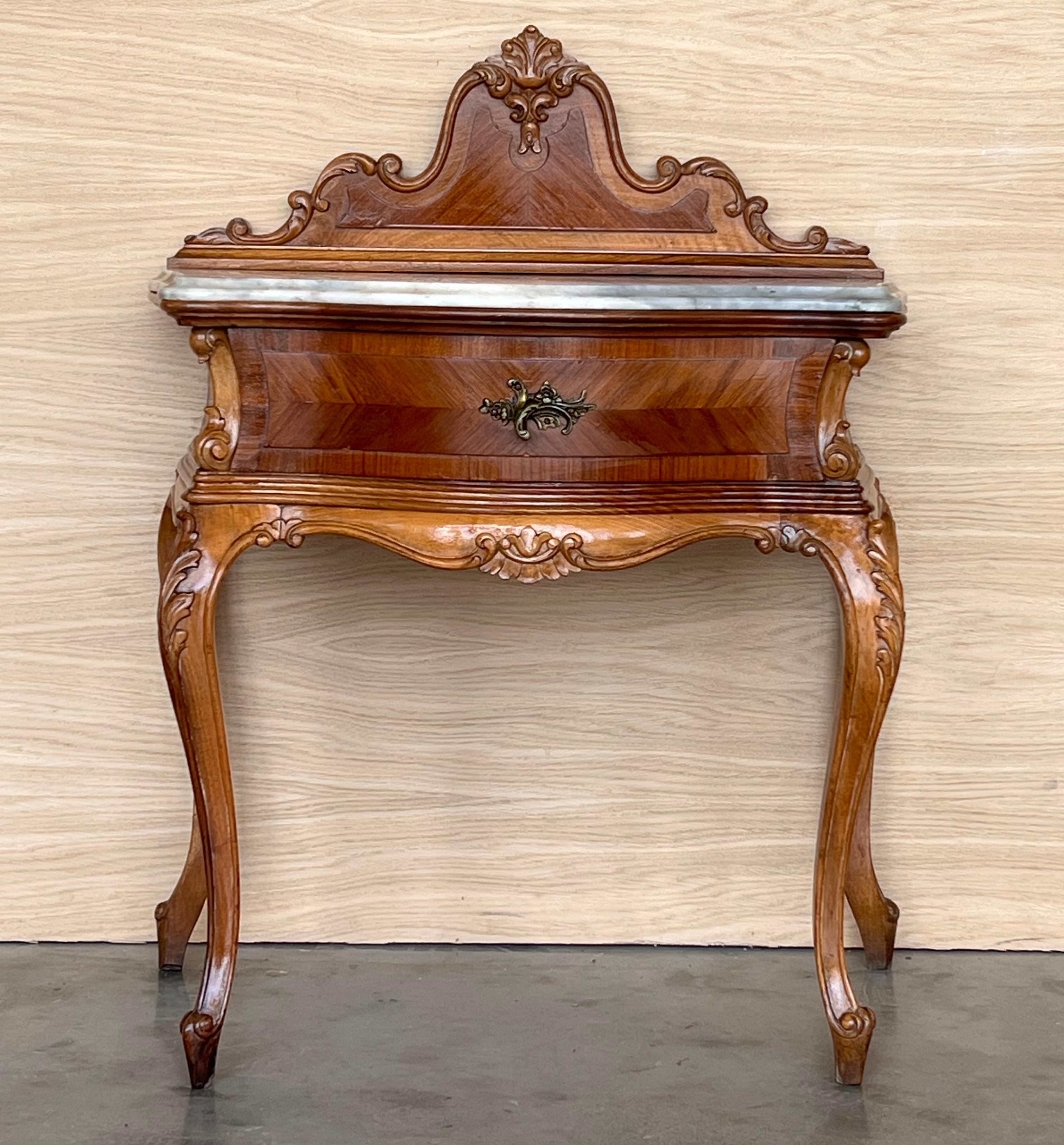 A French walnut drawer nightstands from the learly 20th century with ribbon-carved moldings and carved skirt. This petite French table features a rectangular top with beveled edges, sitting above a drawer simply adorned with a delicate twisted