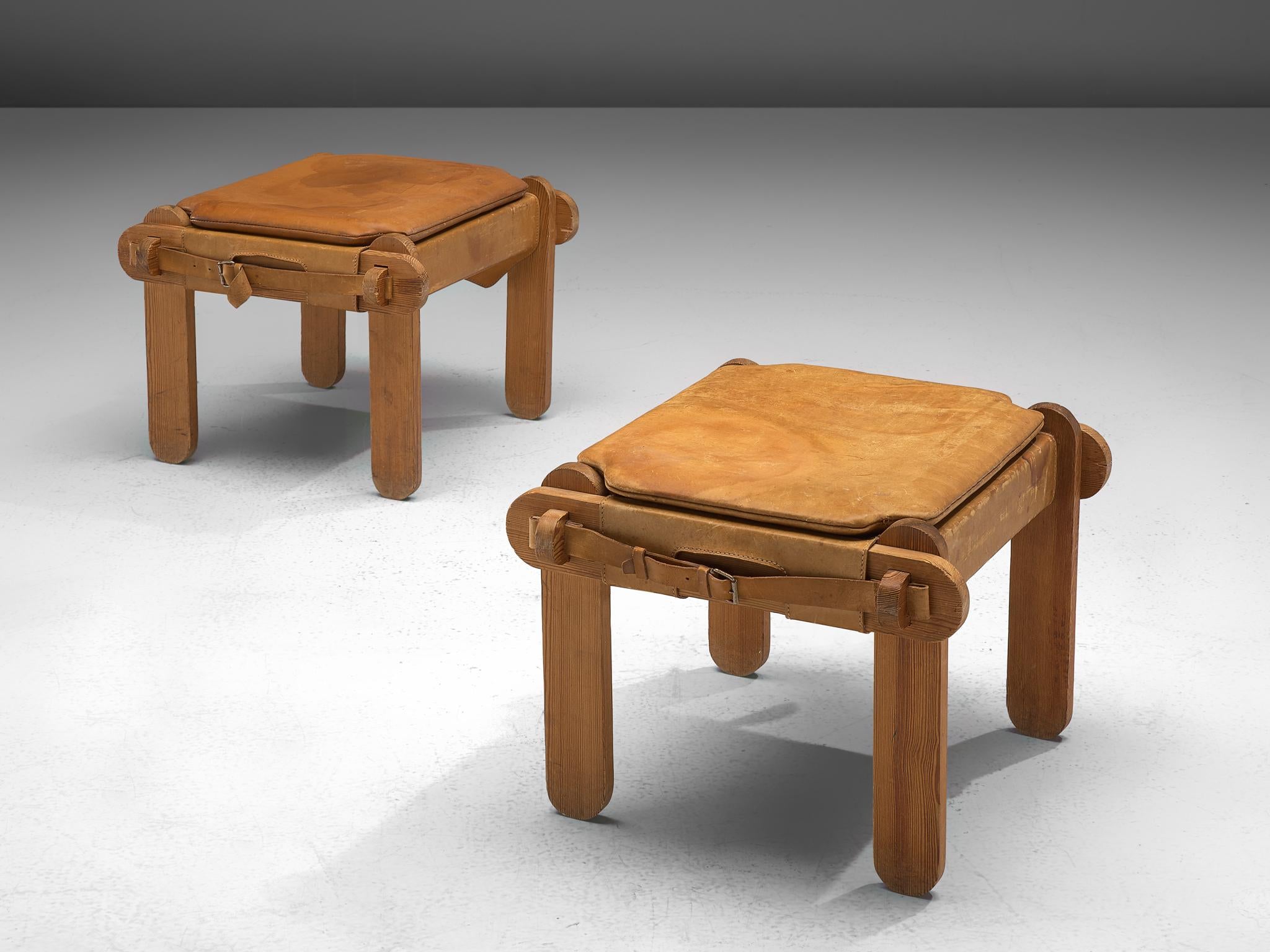 Pair of ottomans, leather, pine, France, 1950s.

This pair of low stools hold a solid crafted frame with characteristic wooden details/joints. The design is original and rare and features geometric, robust frame with rounded edges. The seat is