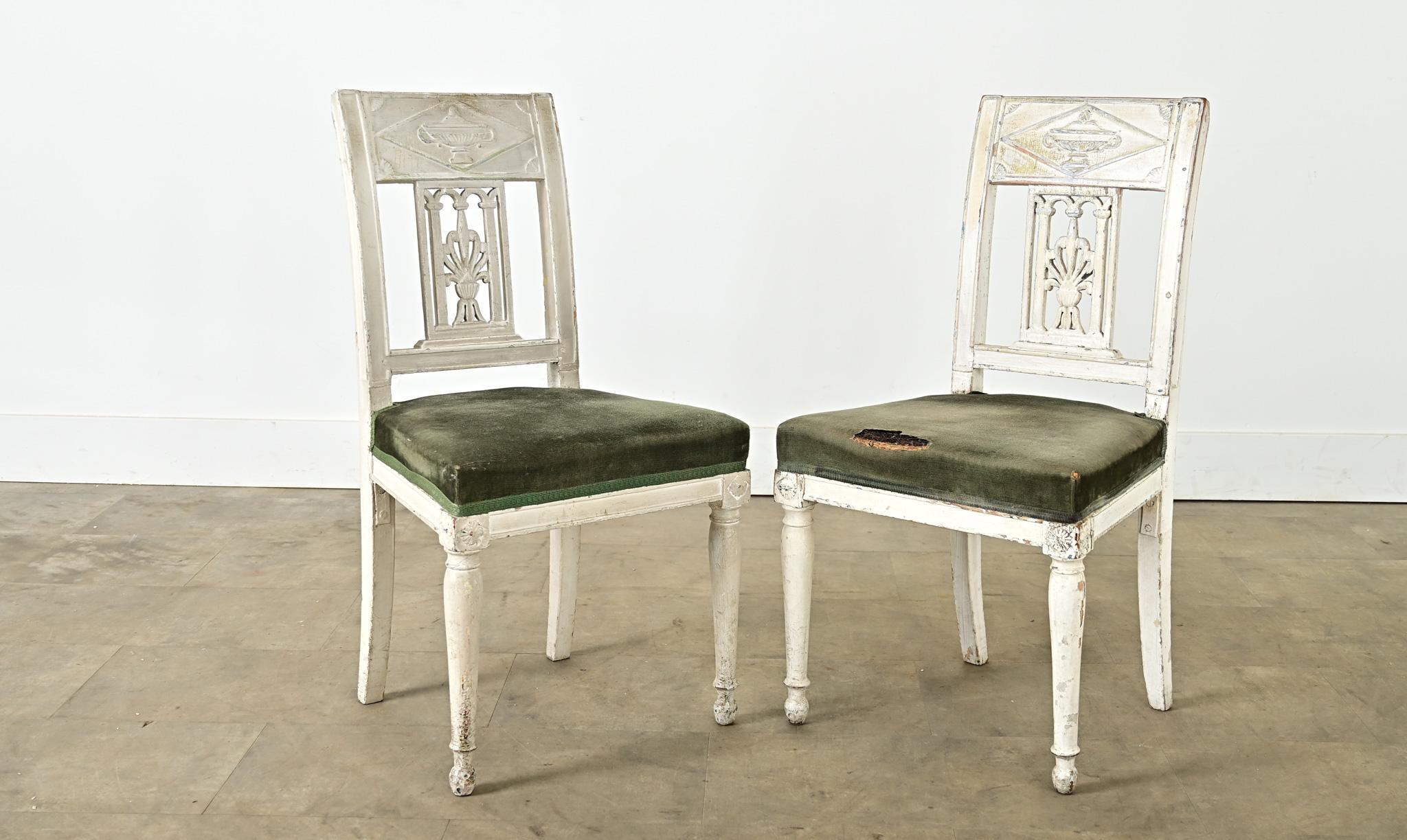 Une paire royale de chaises d'appoint françaises de la période Directoire (vers 1795-1800). Les chaises ont des cadres peints en blanc craie, aujourd'hui patinés en une fine texture craquelée qui adoucit l'imagerie symbolique néoclassique sculptée