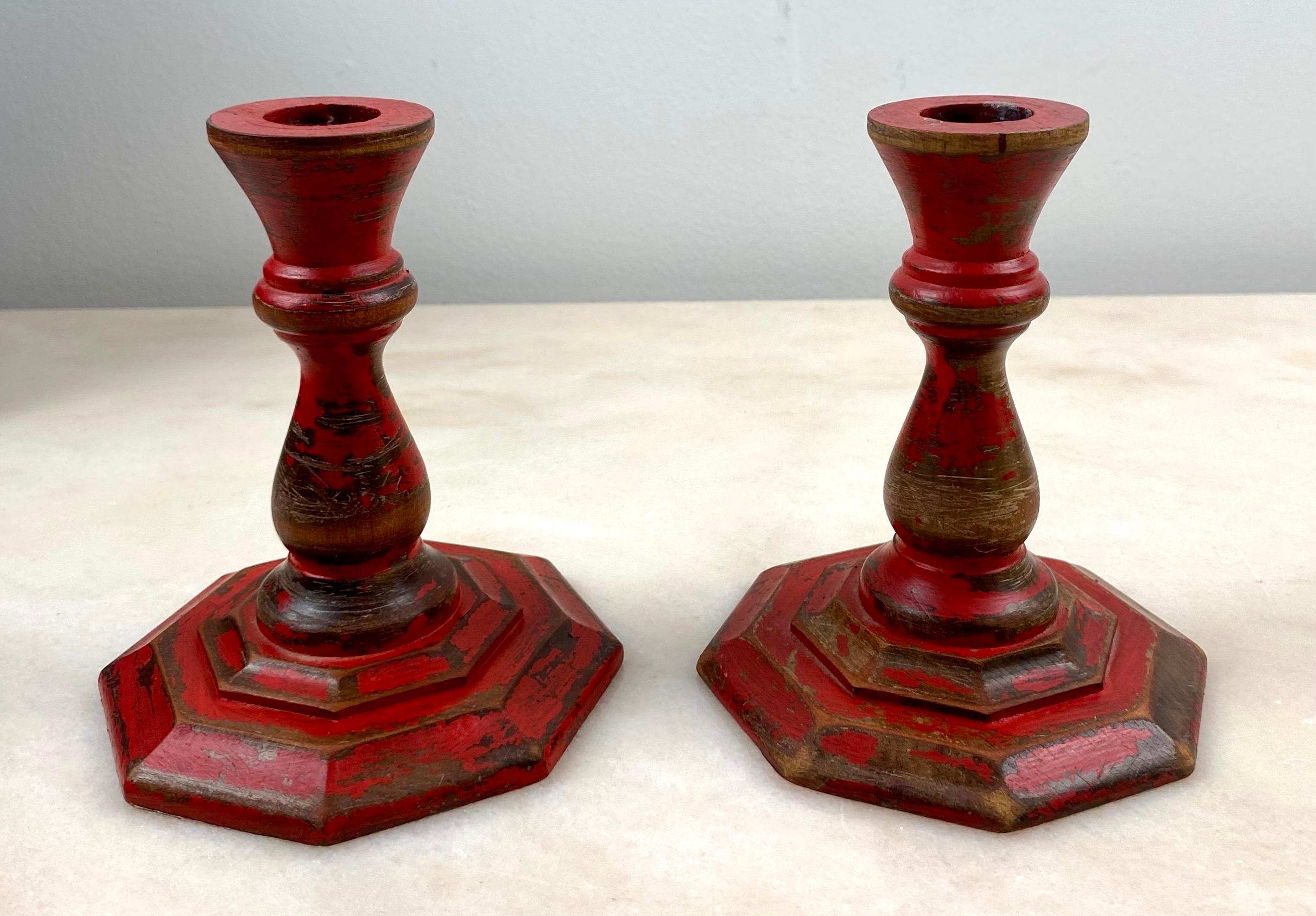 Charming Pair of 19th century wooden candlesticks turned with an old very worn red paint which gives them a very beautiful patina. The underside of the candlesticks is covered with marbled paper similar to an 18th century book binding paper and each