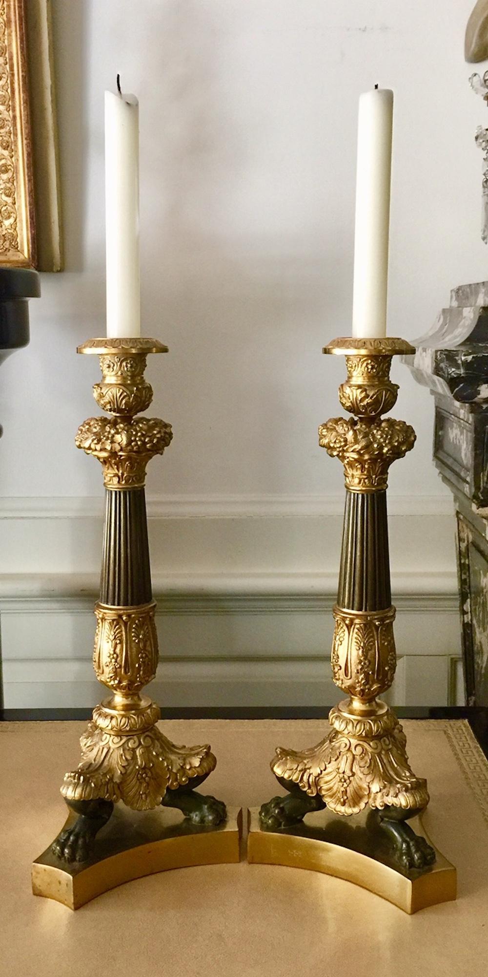 French pair of tall bronze and brass neoclassical Empire style candlesticks
Tall neoclassical pair of gilt and patinated bronze and brass candlesticks with fluted column upon a tripod base finished in lion's paws in brass, the candle holder