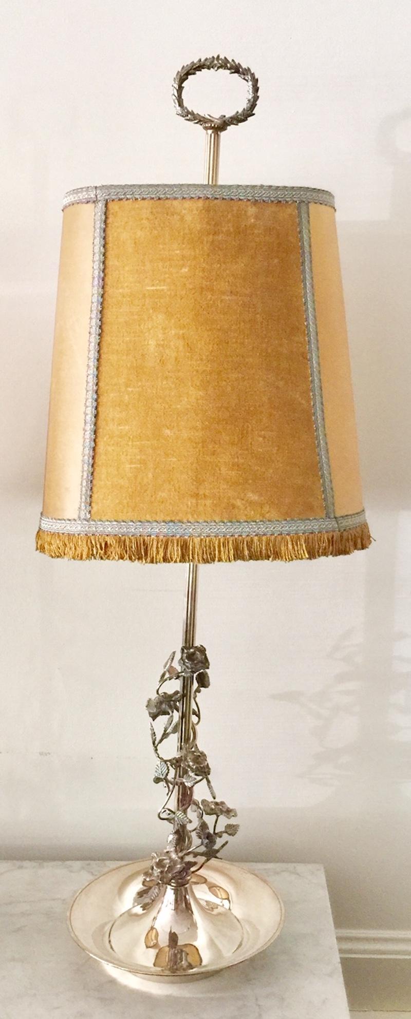 French pair of tall silvered Bouillotte lamps from Aix-en-Provence. The central columns are adorned with a wraparound scroll of silvered metal flower, vinesand leaves. Velvet and parchment shades, passementerie trim. Silvered laurel leaf crown