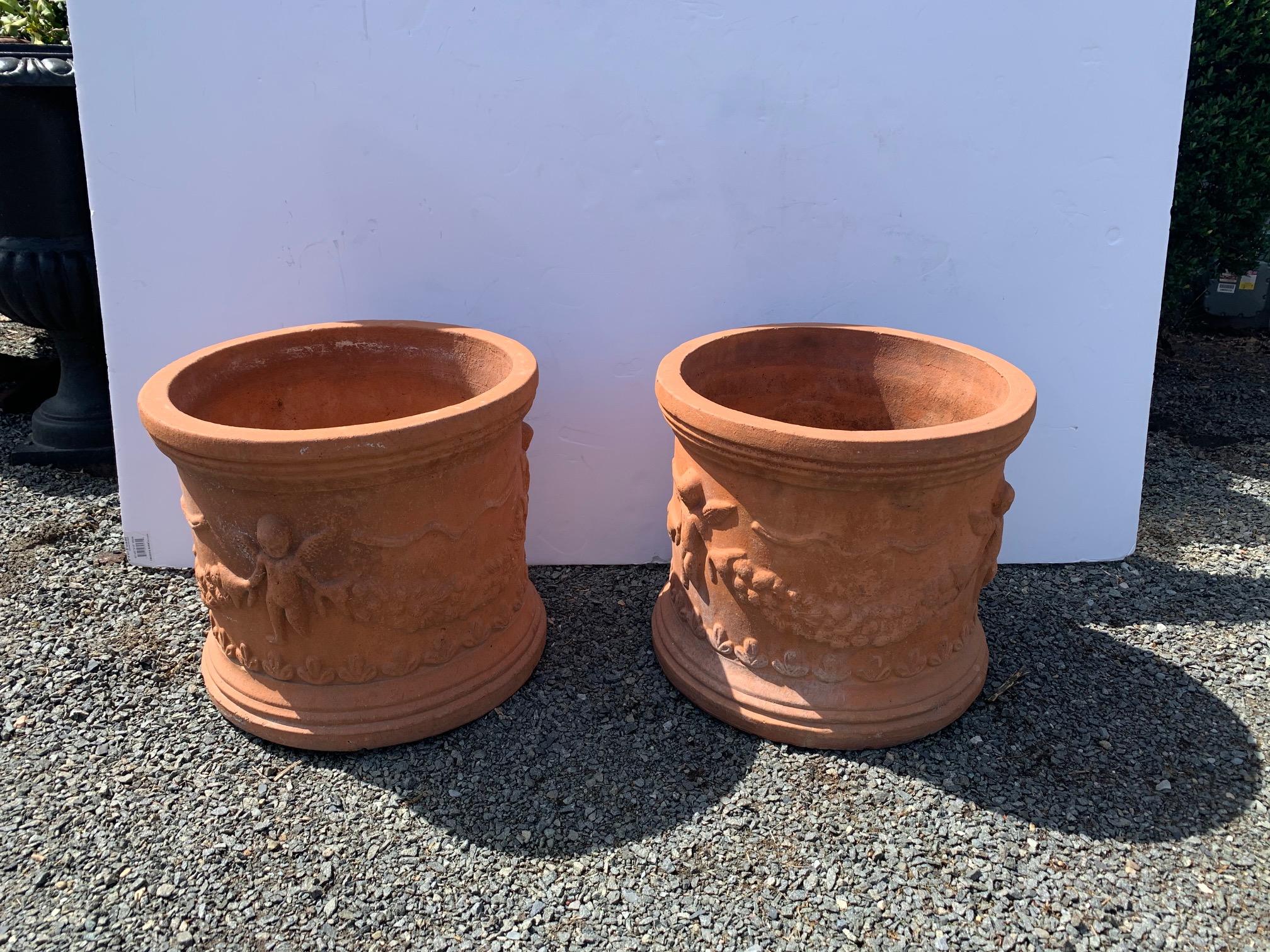 Pair of beautiful French cylindrical terracotta planters having relief decoration of cherubs and pretty swags.