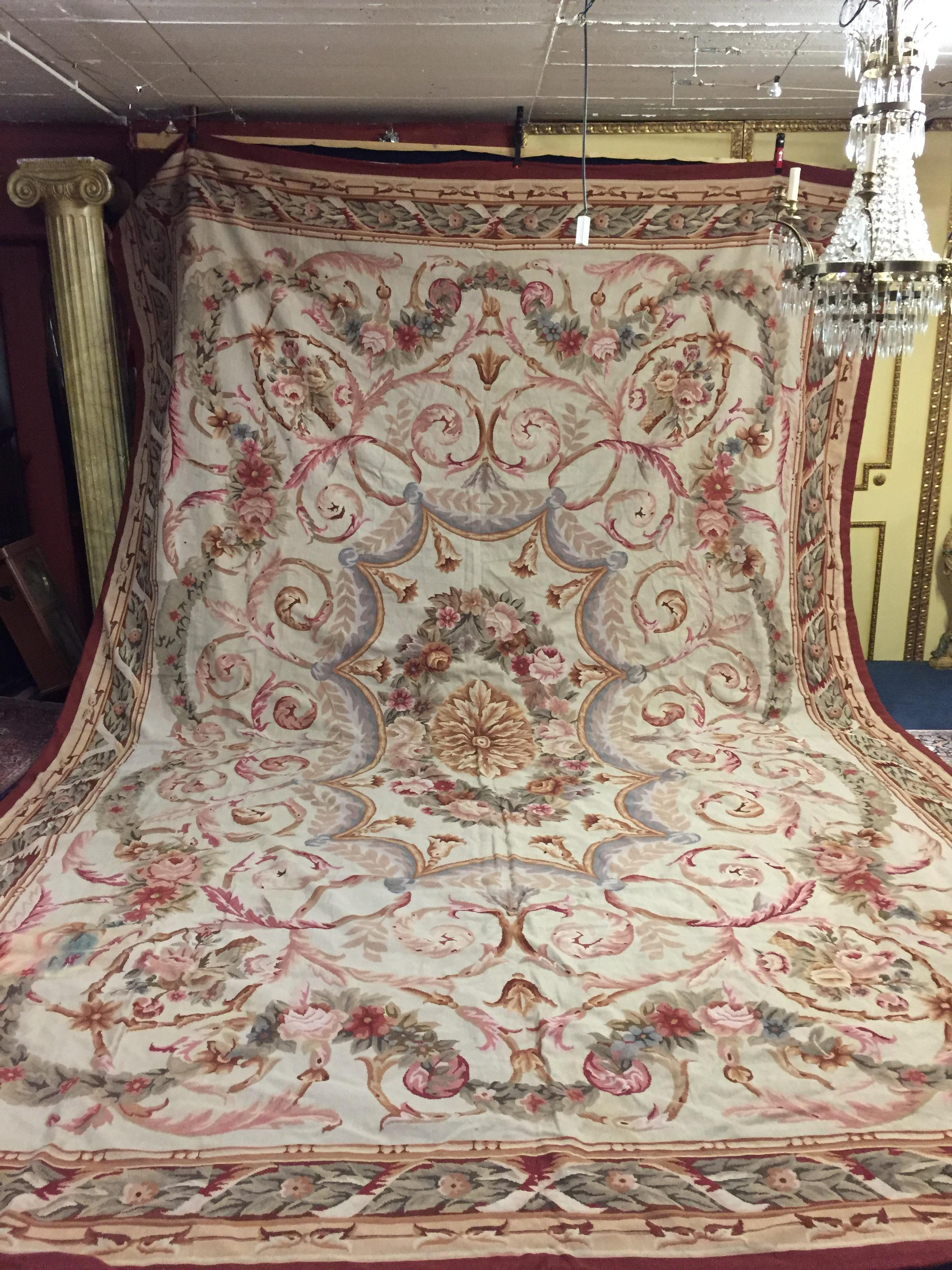 A monumental 20th century French palace size handwoven Aubusson rug. The classical rectangular rug presents with crisp detailing and deep coloration in Beige, Brown, Maroon, and green. The central medallion with a floral bouquet within foliate