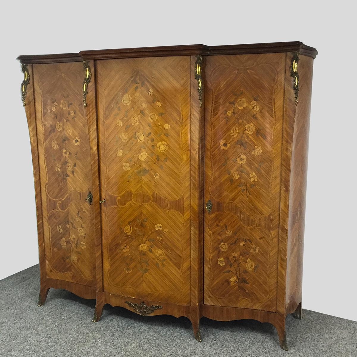 A Beautiful French three doors triple armoire in the style of Louis XV, performed in a marquetry technique, palisander veneer, brass ornaments on the legs and corners. Decorations of roses are displayed on the facade boards. With shelves.