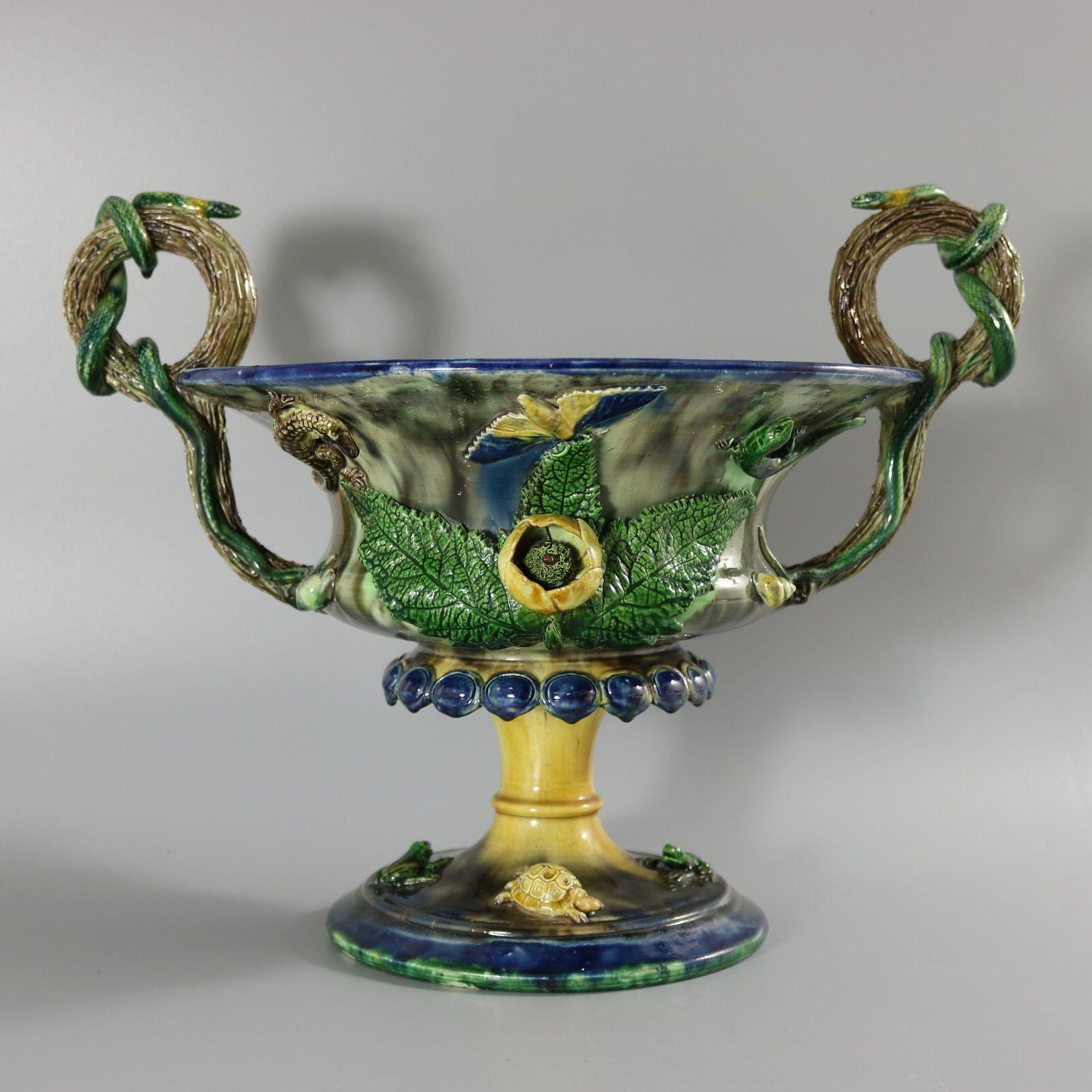 French Palissy Majolica footed jardiniere, which features branch handles with snakes coiled around. The sides of the bowl have applied flowers, leaves, moths lizards and shells. The foot of the planter has a pair of frogs and tortoises. Colouration:
