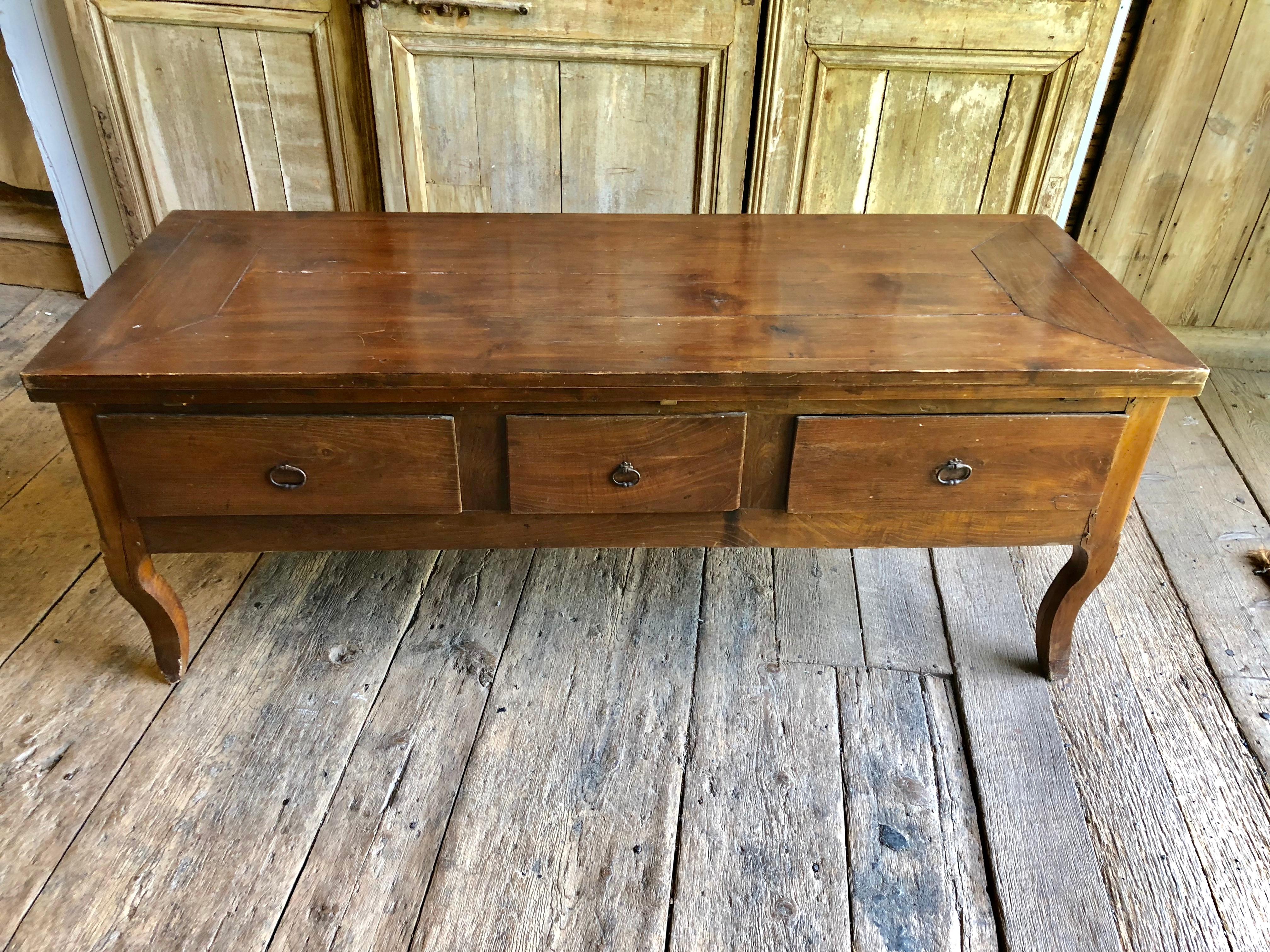 A mid-18th century French table with three large drawers on cabriole legs, having been converted to a dining table with ingenious pull-out leaf extensions on the sides. Cherrywood and oak.