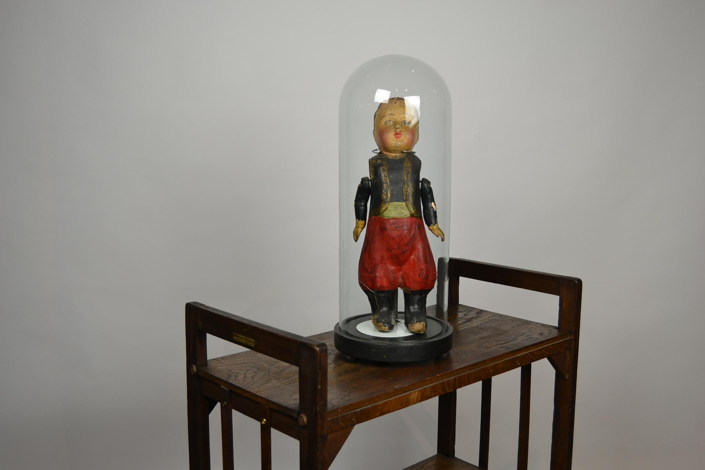 Great piece of Folk Art.
An antique doll made of papier-mâché, hand painted.
Through the years this French doll got a great old patina, so a lot of history and charm.
Represented and delivered underneath an antique hand blown glass dome.

The