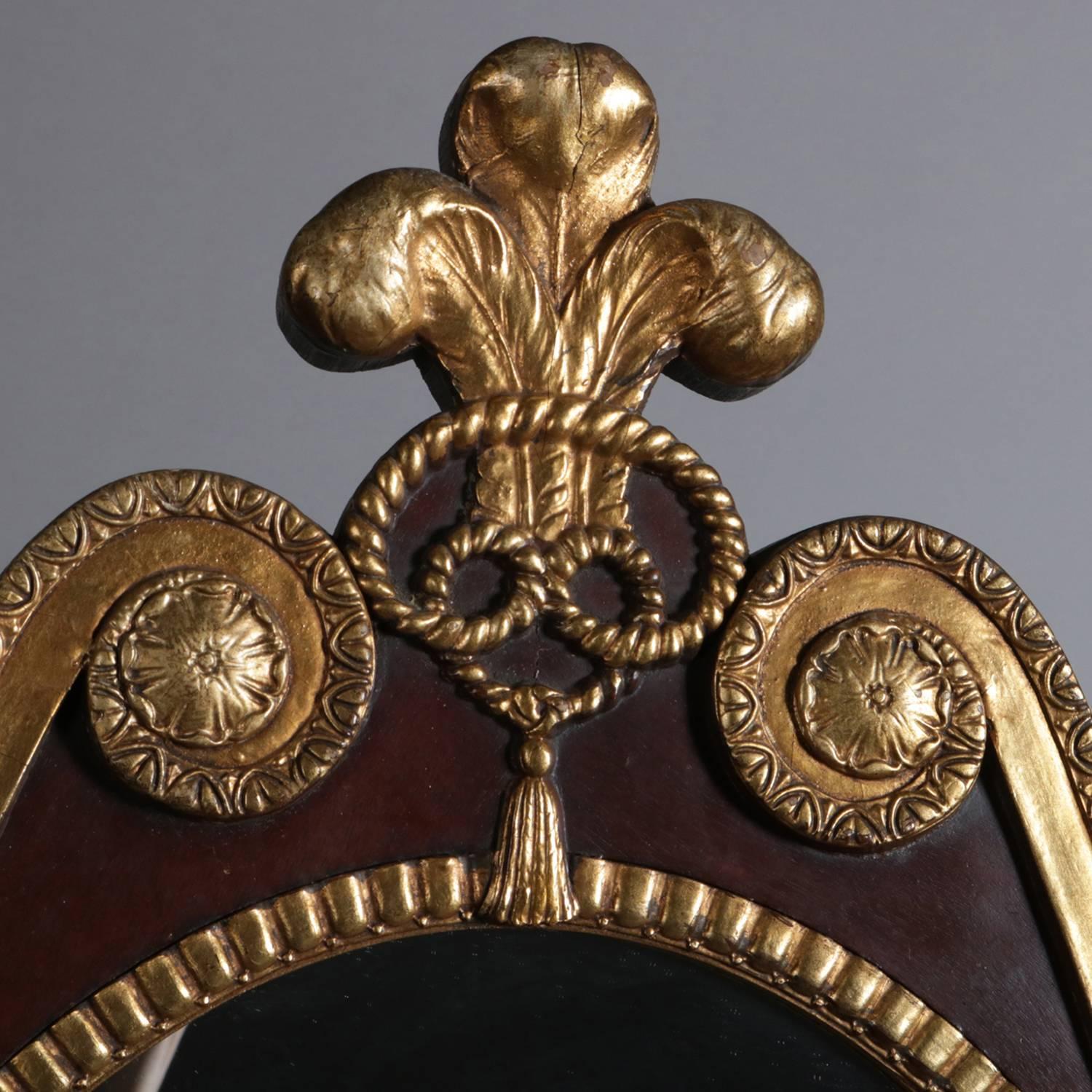 French parcel-gilt mahogany Federal style wall mirror features shield form having gilt Fluer de Lis finial with flanking scroll form crest, gilt and reeded surround terminate at each shoulder with Corbeille a Fleurs (basket of flowers), 20th