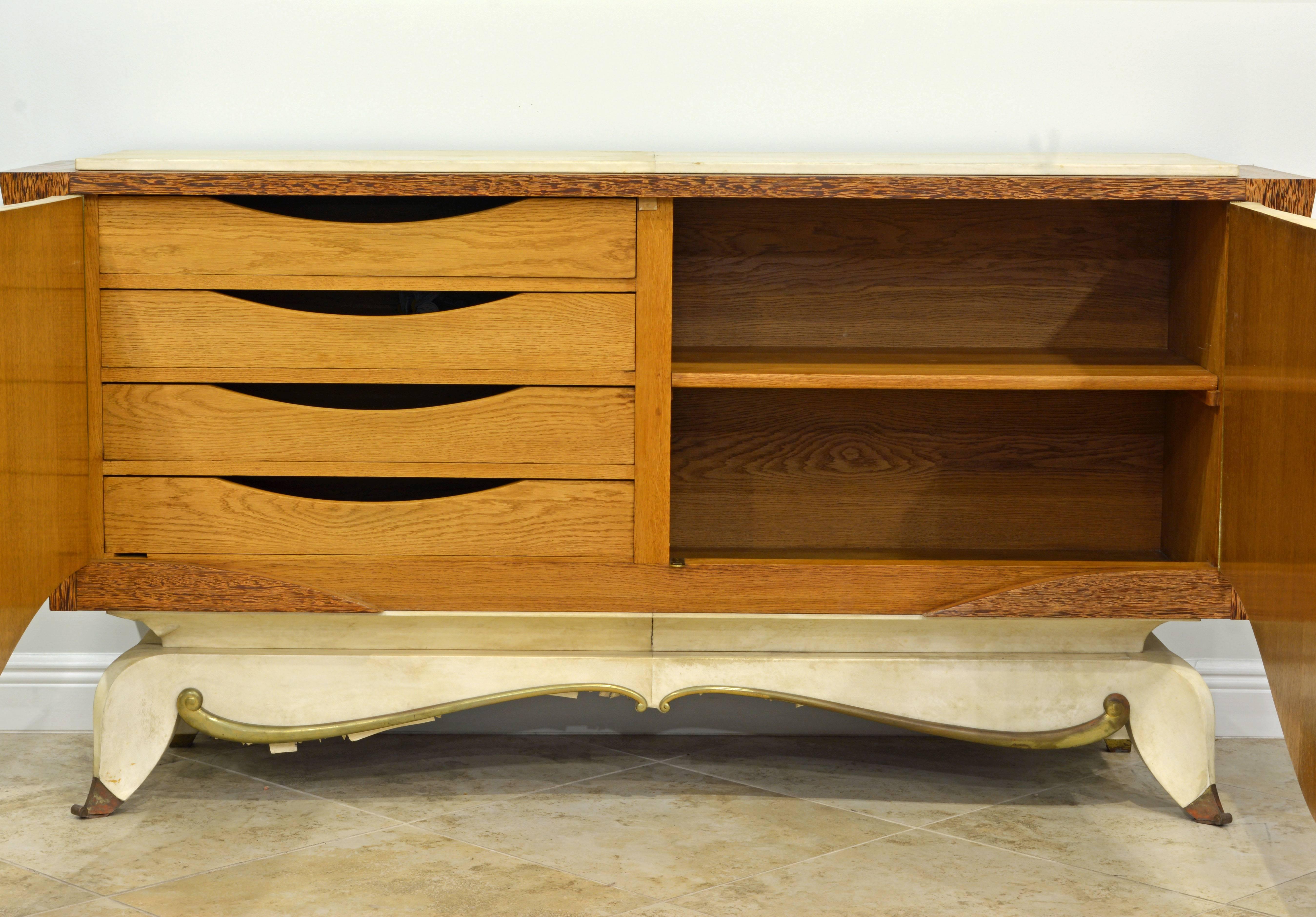 This sculptural piece of French Art Deco furniture features a combination of parchment clad surfaces and wonderful Macassar wood accented by a scrolled bronze trim and bronze sabots. Very unique and elegant. The two-shaped and curbed doors open up