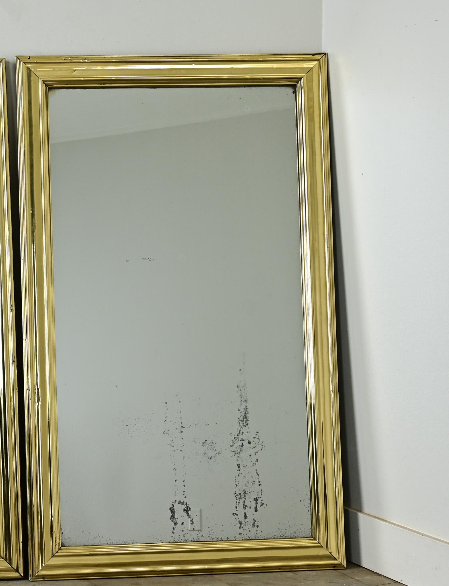 Splendida coppia di specchi francesi con splendide cornici in ottone lucido e lastre di specchio originali. Le cornici simmetriche possono essere montate in entrambe le direzioni: sopra la boiserie di una sala da pranzo, sopra la toilette di un