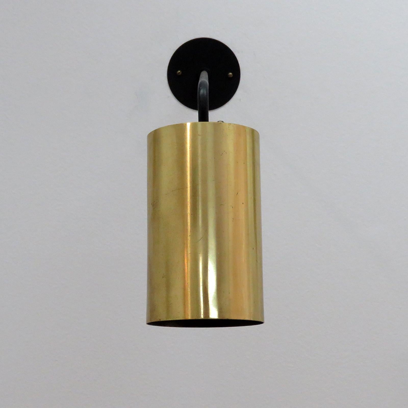 Great understated French wall light by Parscot, with brass cylinder adjustable via a ball joint on a long black enameled arm, can be used as wall or ceiling mount, wired for US standards, one E27 socket, max. wattage 100w or LED equivalent,