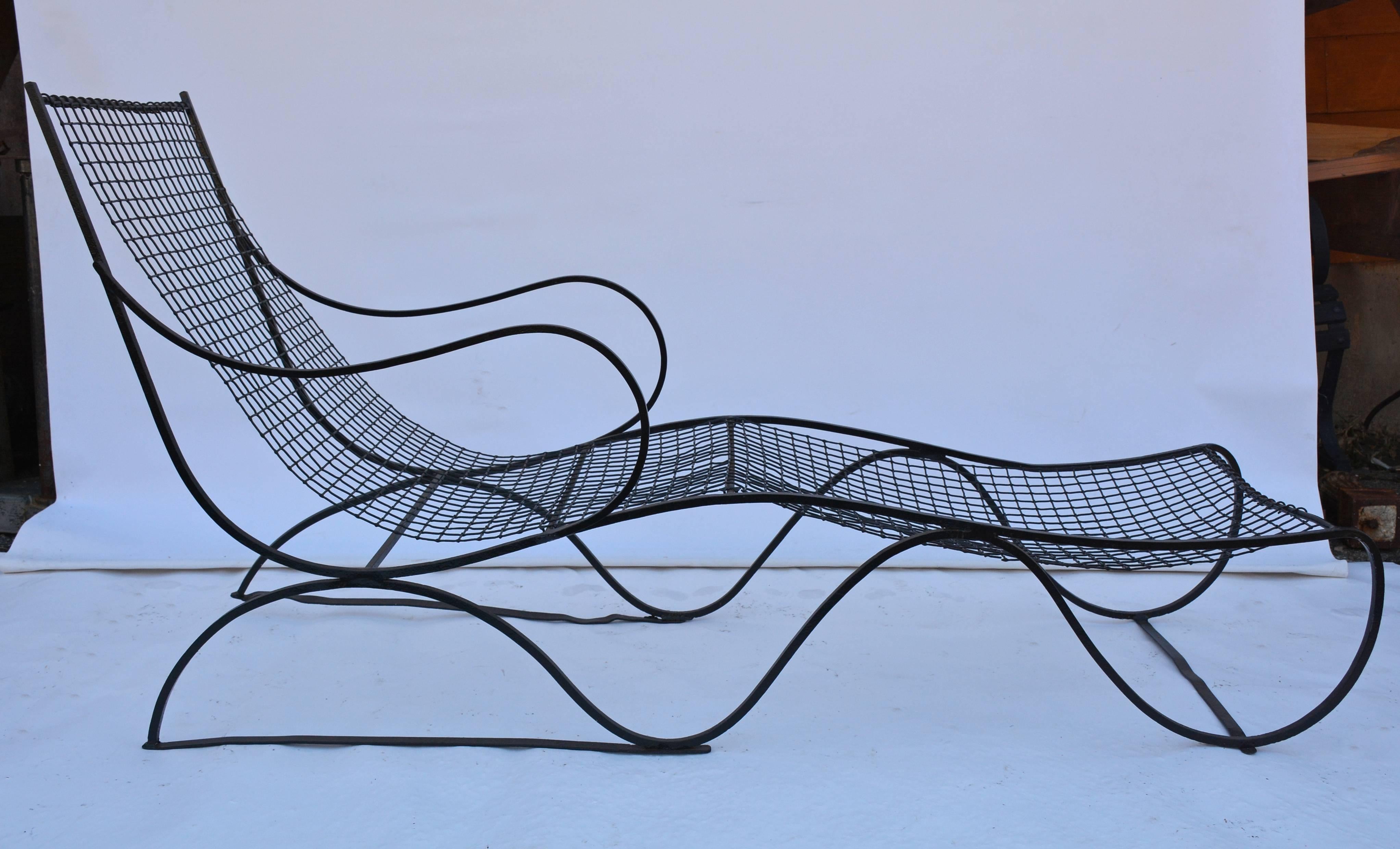 Die wellenförmige, schwarze Garten-Chaise-Lounge aus Metall ist relativ leicht und lässt sich leicht bewegen. Der Sitz ist an den Kniekehlen hochgezogen, was ihn sehr bequem macht. Das Netz könnte ein gepolstertes flaches Kissen aufnehmen. Neu