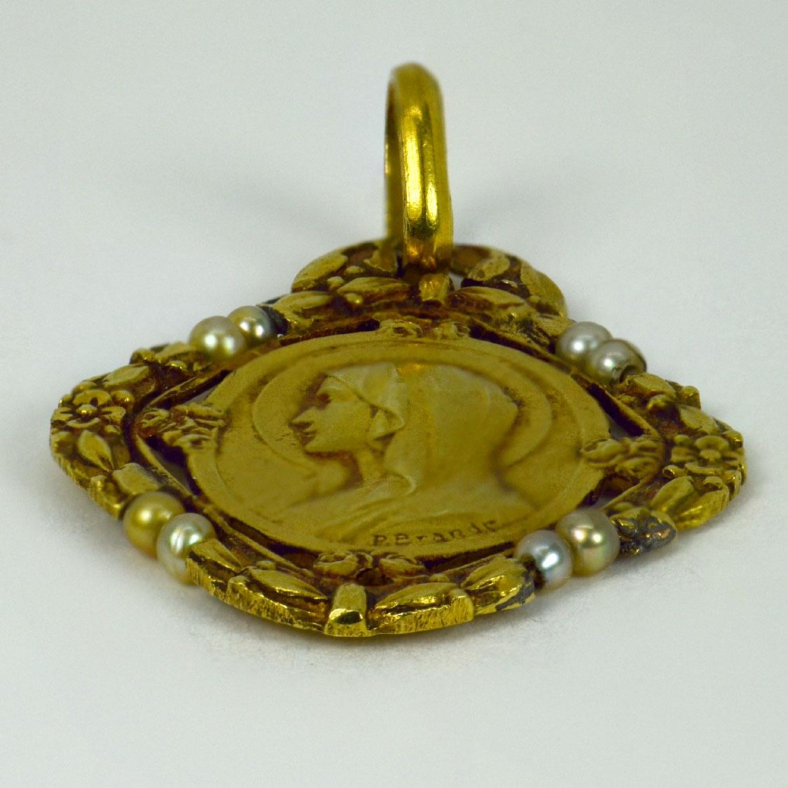 A French 18 karat (18K) yellow gold charm pendant designed as a medal depicting the Virgin Mary within a frame of roses and flowers set with eight natural seed pearls. Signed P. Brandt for Paul Brandt. Stamped with the eagles head for French