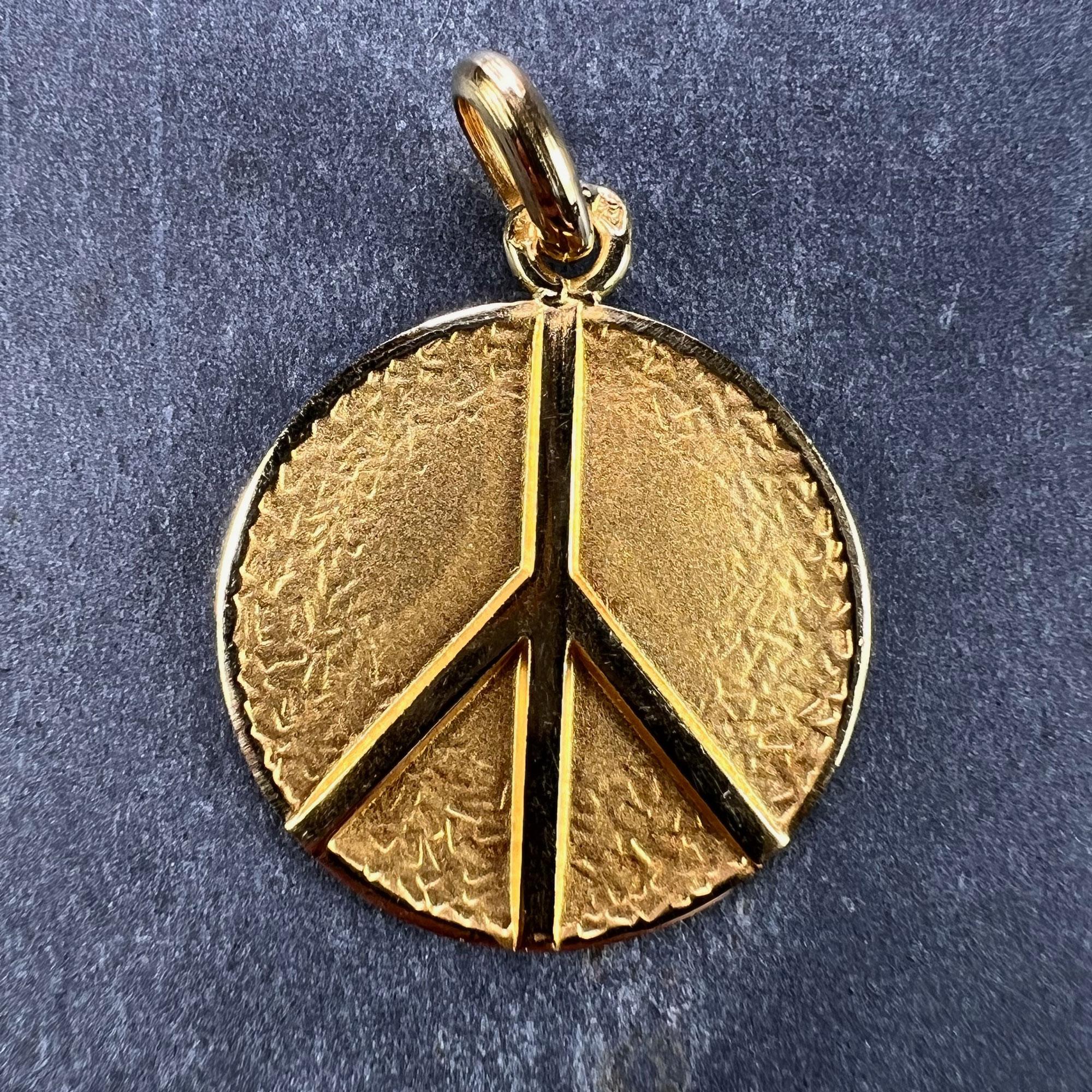 A French 18 karat (18K) yellow gold charm pendant designed as a medal depicting a peace sign on a textured background. Stamped with the eagle’s head for 18 karat gold and French manufacture with an unknown makers mark.

Dimensions: 2.2 x 1.9 x 0.12