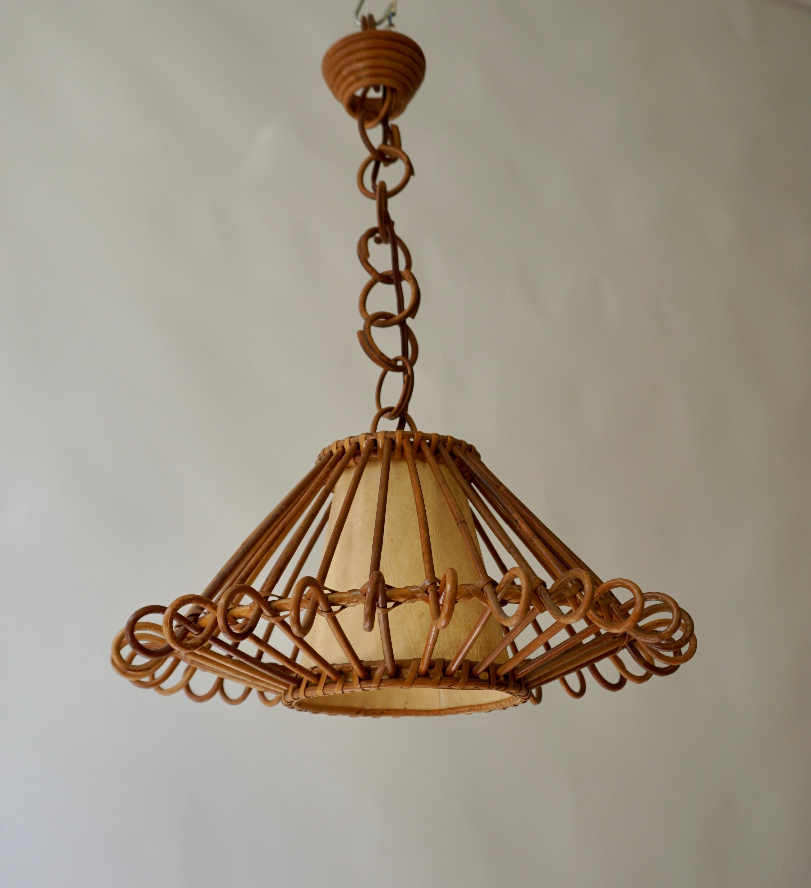 Bamboo and rattan french pendant lamp. Mid-century round piece with an interior parchment paper shade with a sort of linen texture.

French Modernist Rattan Pendant Lamp or Lantern. France, 1950s. This eye-catching rattan chandelier features a