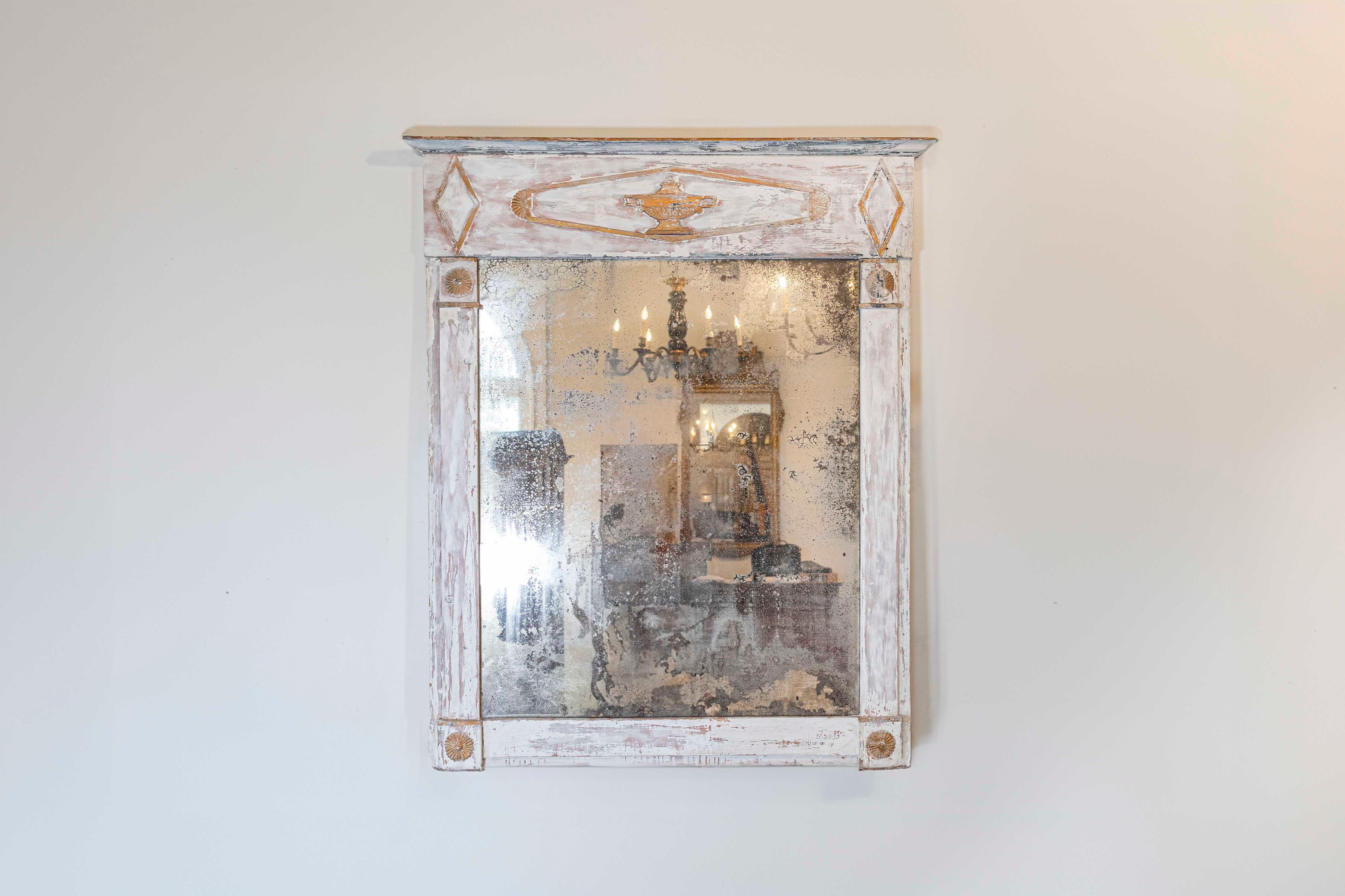 Specchio trumeau del periodo Directoire francese della fine del XVIII secolo con accenti dorati, urna intagliata, verniciatura e specchio rovinati. Questo specchio del Direttorio francese presenta un'elegante silhouette lineare. La finitura in