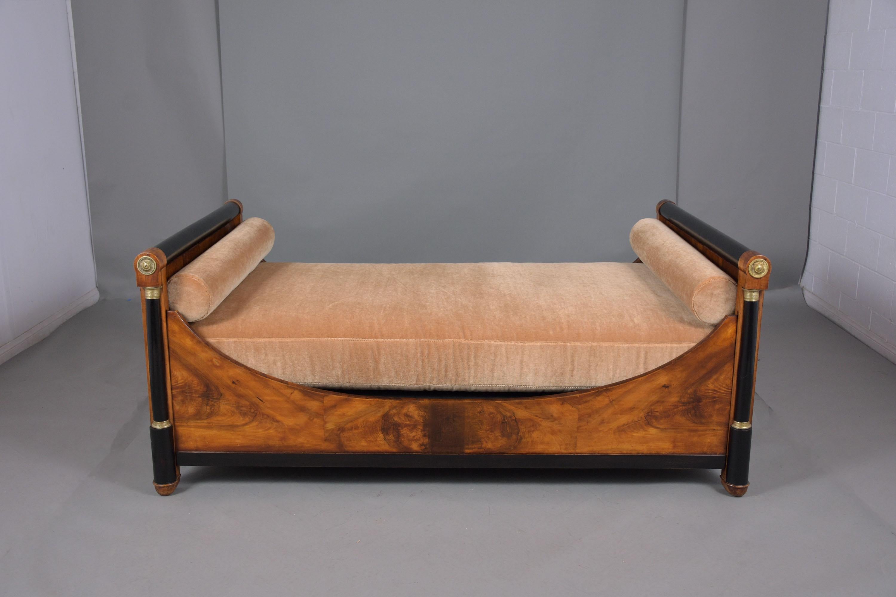An extraordinary late 18th-century empire daybed handcrafted out of walnut wood and been professionally restored by our team of in-house craftsmen. This elegant daybed features a straigh headboard front columns with bronze ornaments, and molding