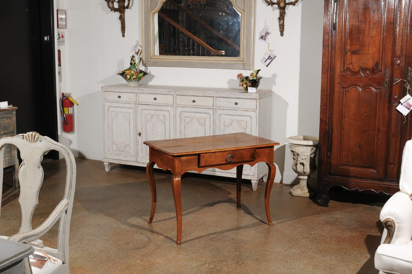 A French Period Louis XV walnut table from the mid-18th century, with single drawer, scalloped apron and cabriole legs. Born in France during the reign of Louis XV nicknamed 
