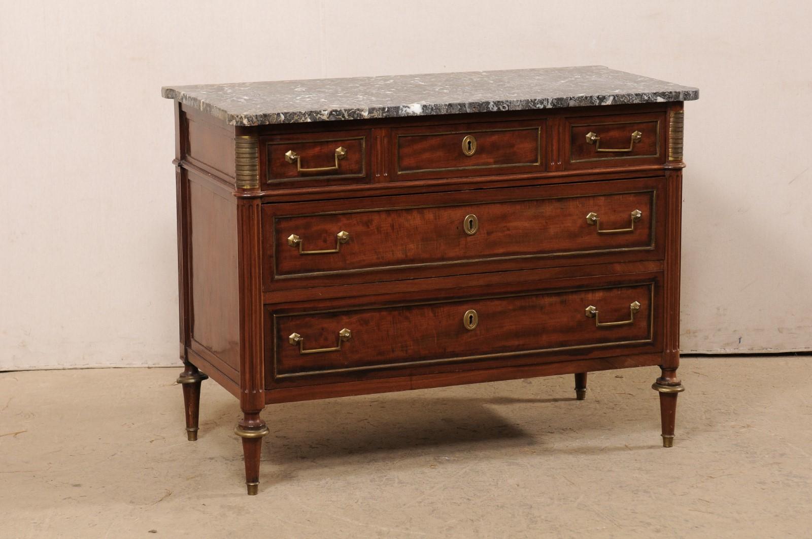 A French Neoclassical period chest with its original marble top from the early 19th century. This antique commode from France features a rectangular-shaped marble top, with pronounced rounded corners, which rests atop a neoclassically carved case