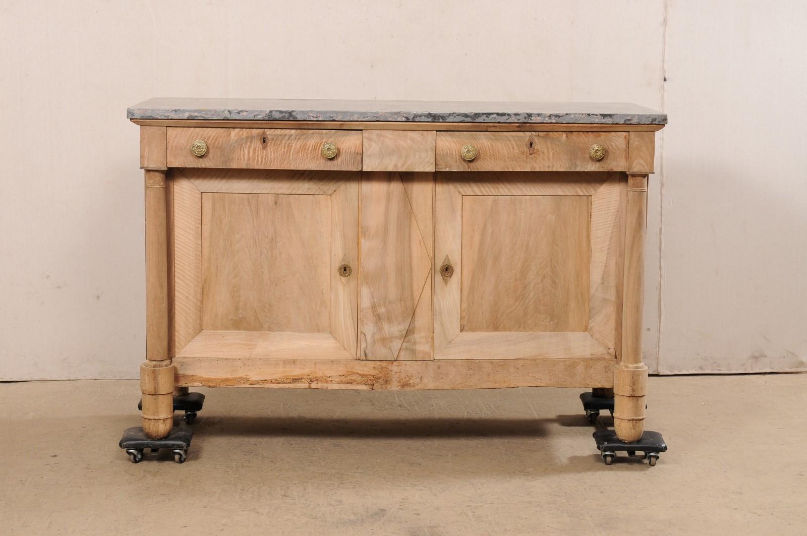 A French neoclassical period buffet cabinet, with unusual marble top and stunning brass hardware, from the early 19th century. This antique cabinet from France has a rectangular-shaped top with gray marble, resting atop the body/case which houses a